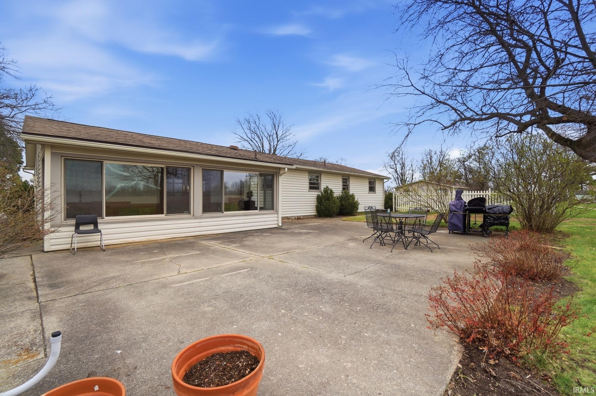 Rear view of property featuring a patio, roof with shingles, and outdoor dining space