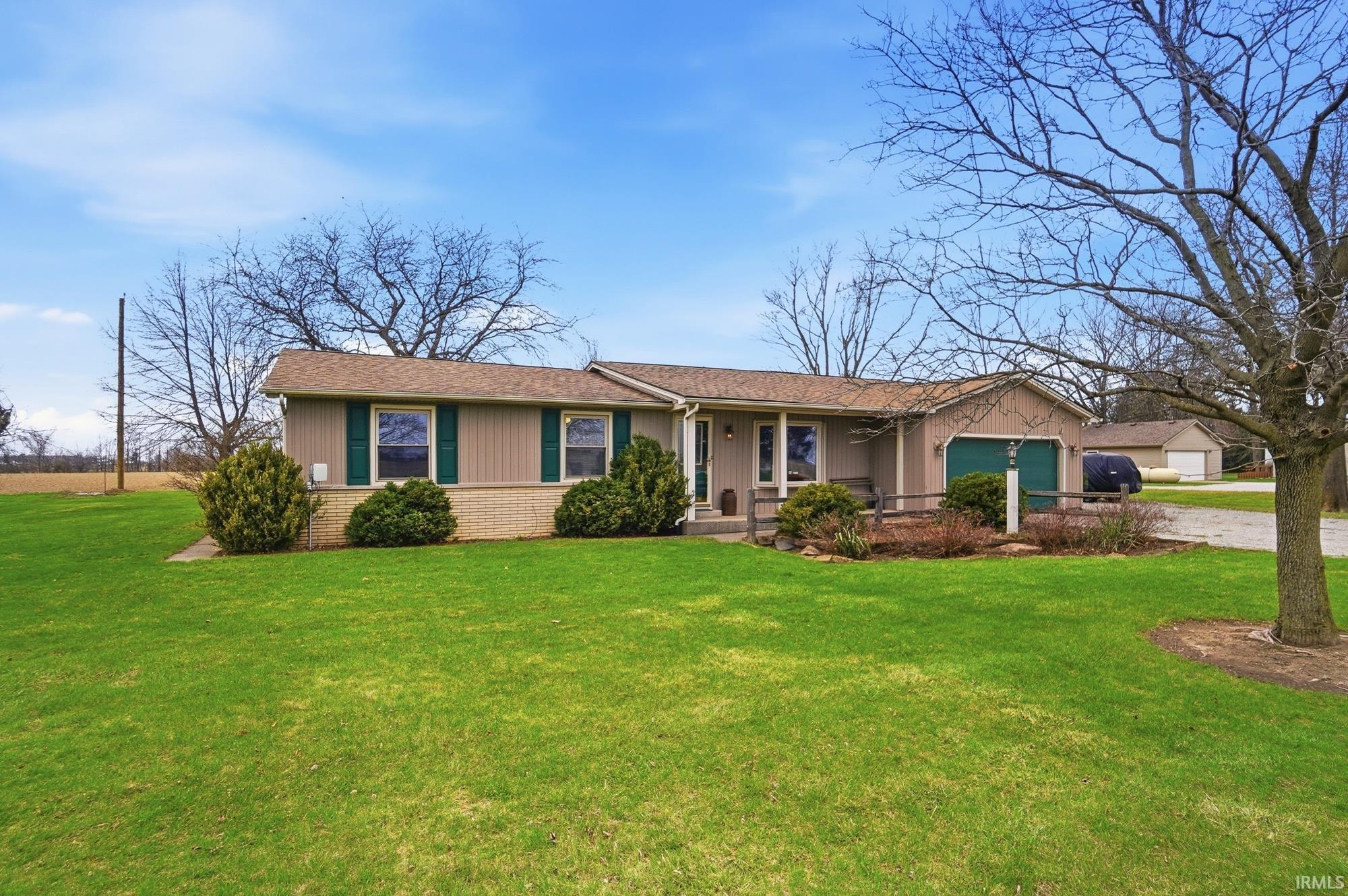 Ranch-style house with brick siding, covered porch, a garage, driveway, and a front lawn
