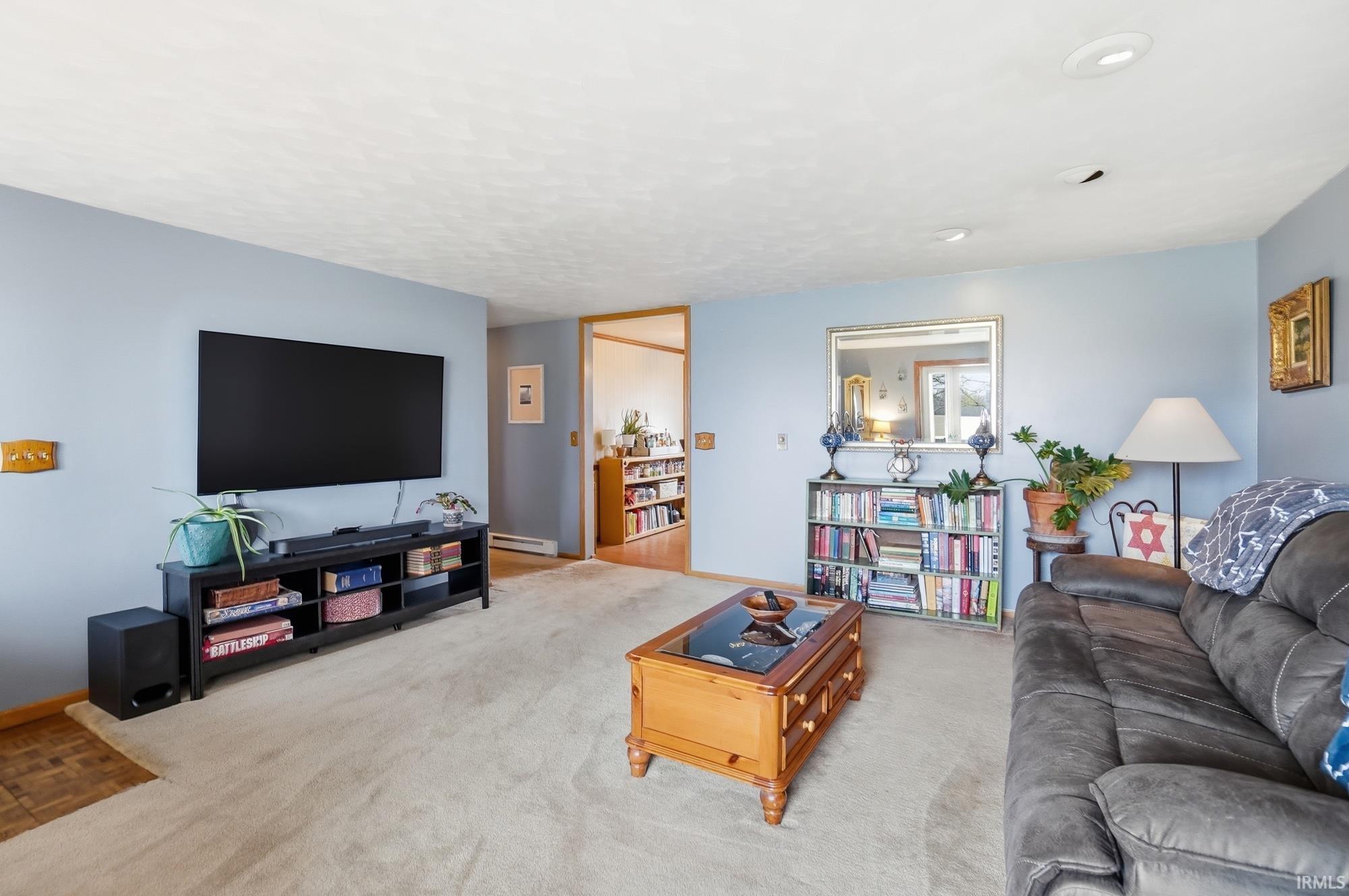 Carpeted living room featuring a baseboard radiator and baseboards