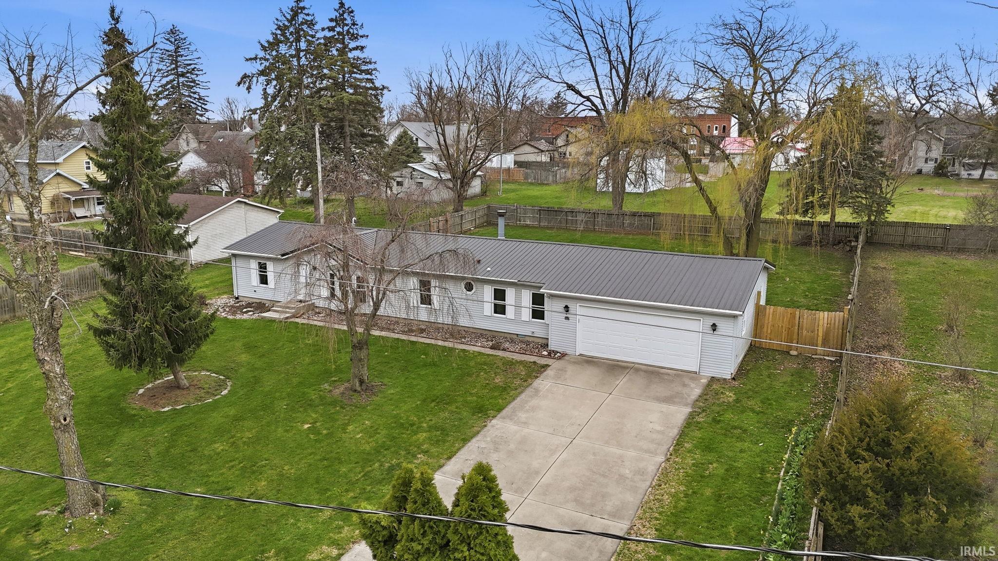 View of front of property featuring a metal roof, concrete driveway, an attached garage, and a residential view