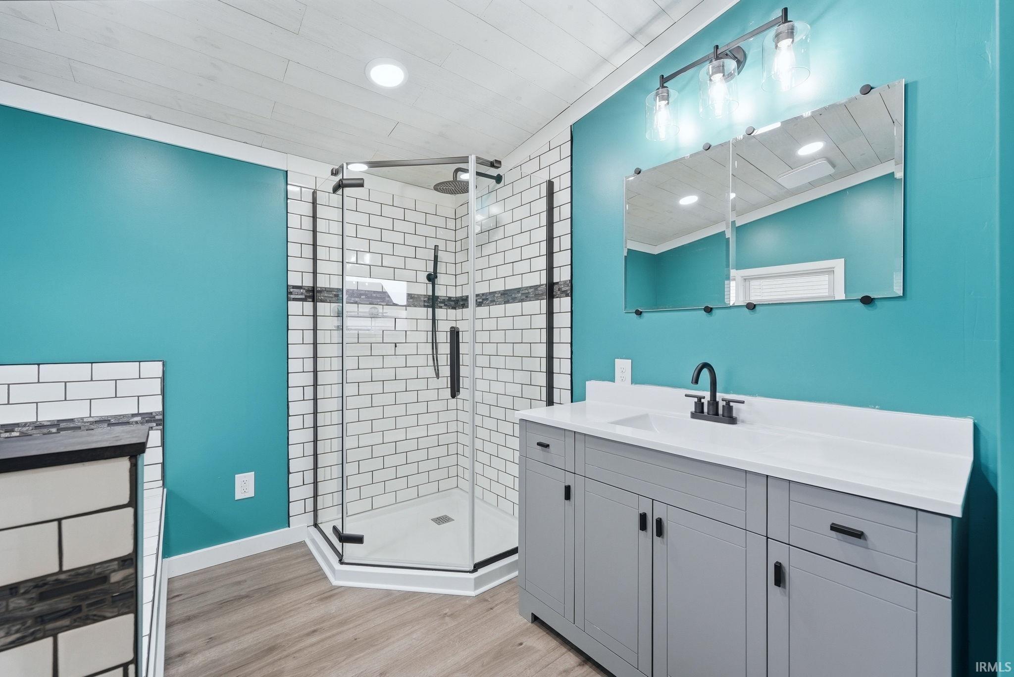 Bathroom featuring vanity, light wood-style flooring, a shower stall, and recessed lighting