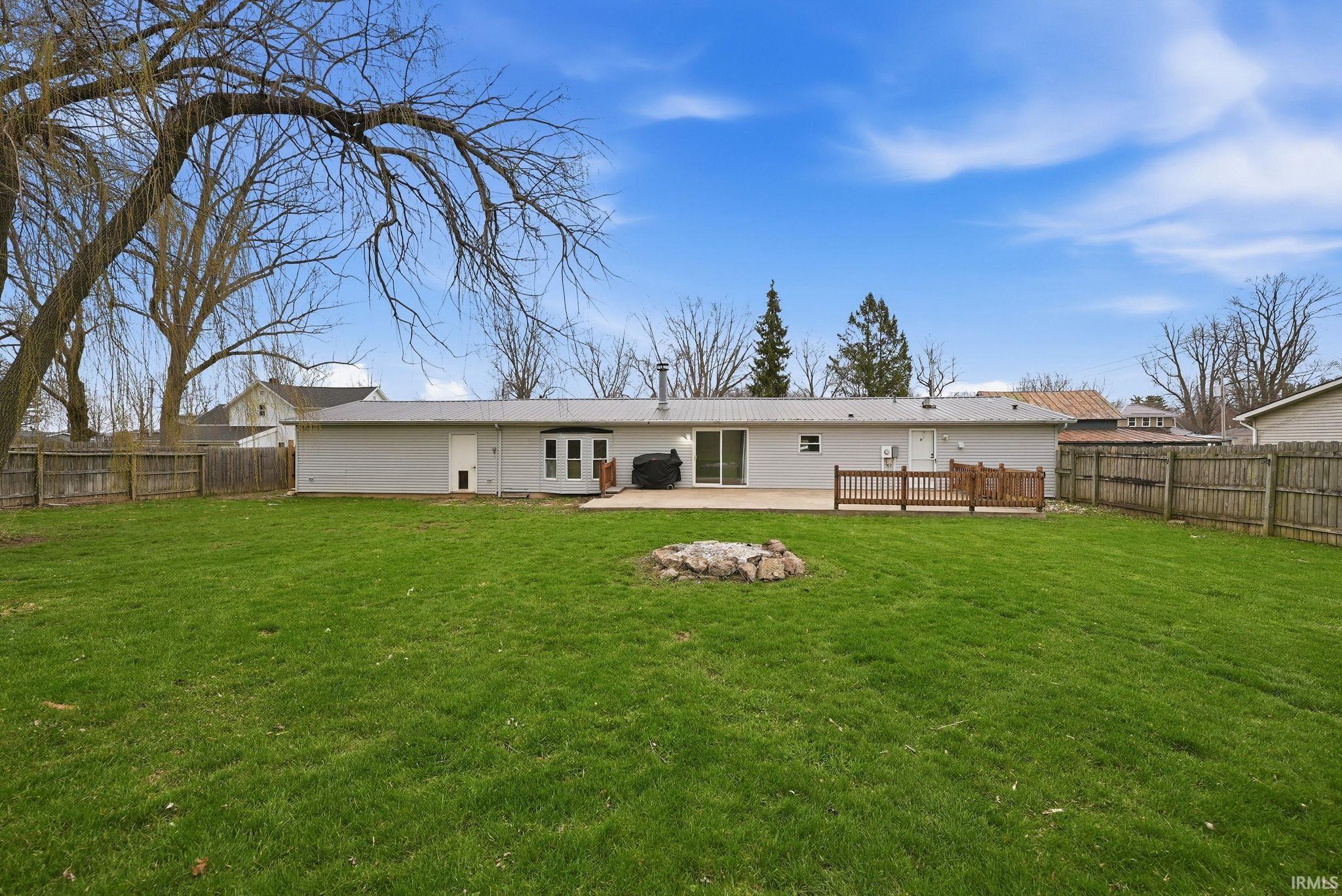 Back of property with a fenced backyard, a patio, and a metal roof