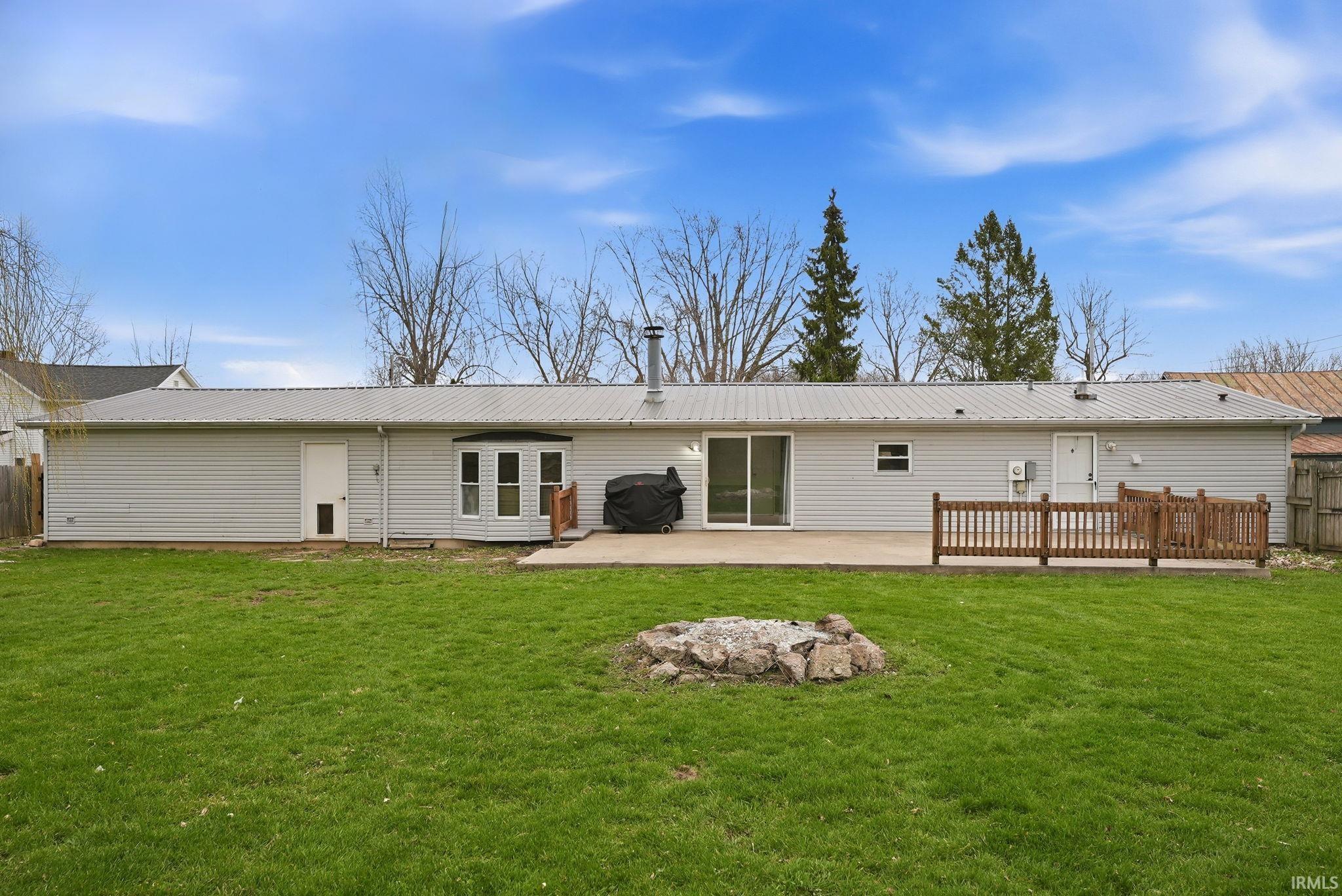 Rear view of house featuring a metal roof, a patio area, and a fire pit