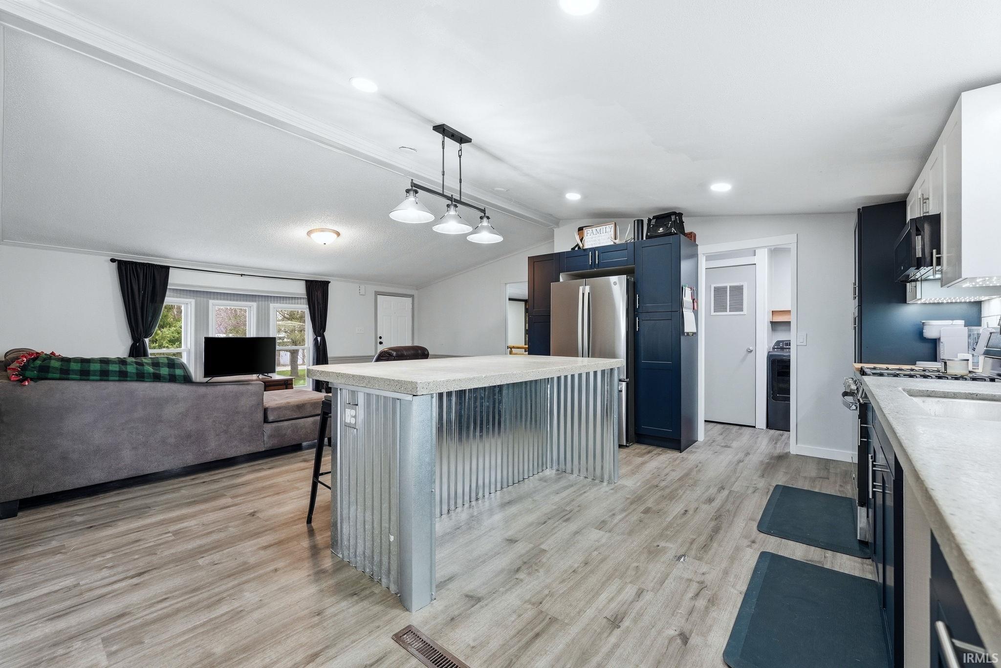 Kitchen with open floor plan, a breakfast bar, light wood finished floors, a kitchen island, and stainless steel appliances