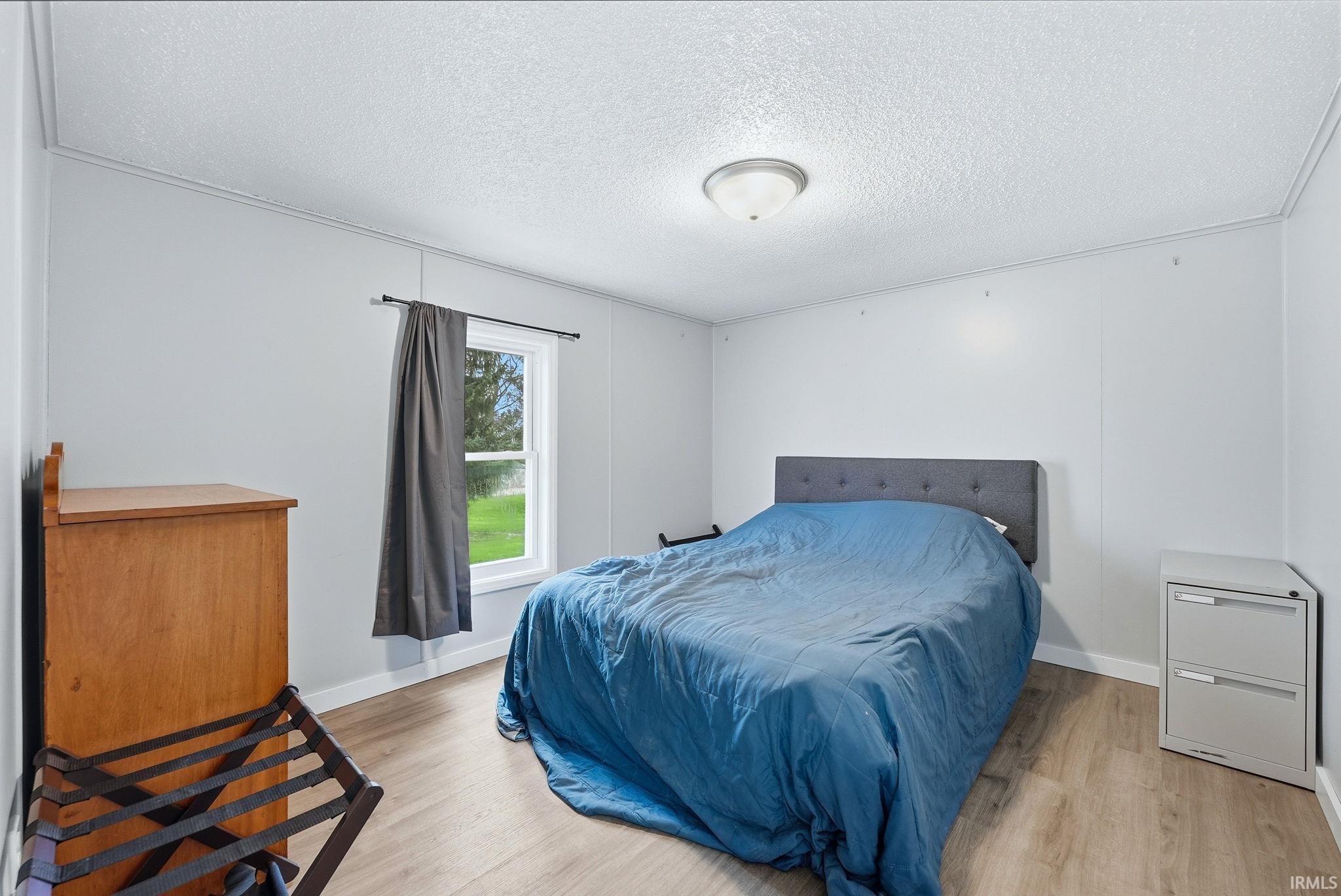 Bedroom with light wood-style floors and a textured ceiling