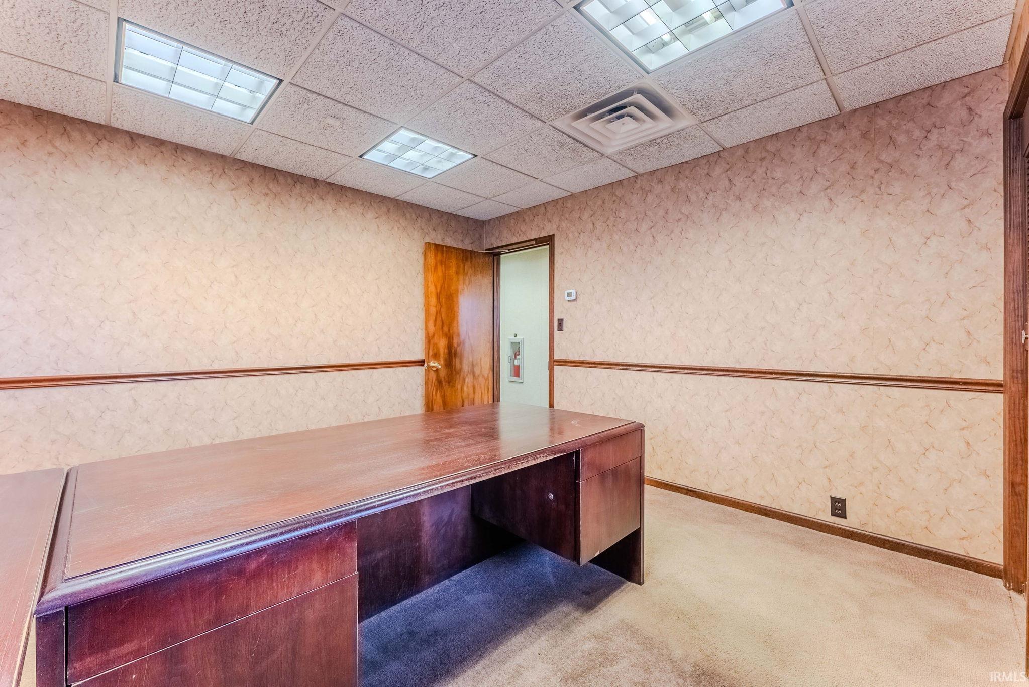 Unfurnished office featuring a drop ceiling and wallpapered walls