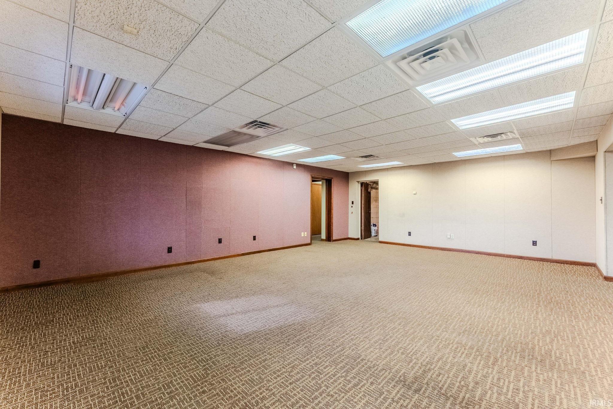 Below grade area with light colored carpet and a drop ceiling