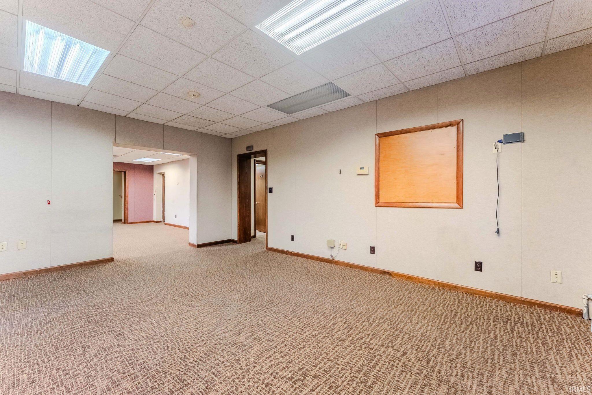 Empty room featuring a paneled ceiling and light colored carpet