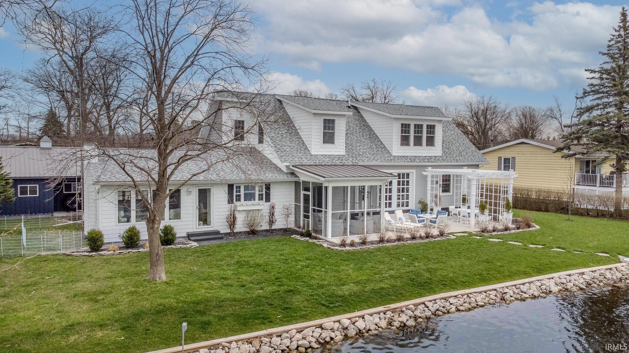 Back of house with a sunroom, a shingled roof, and a water view