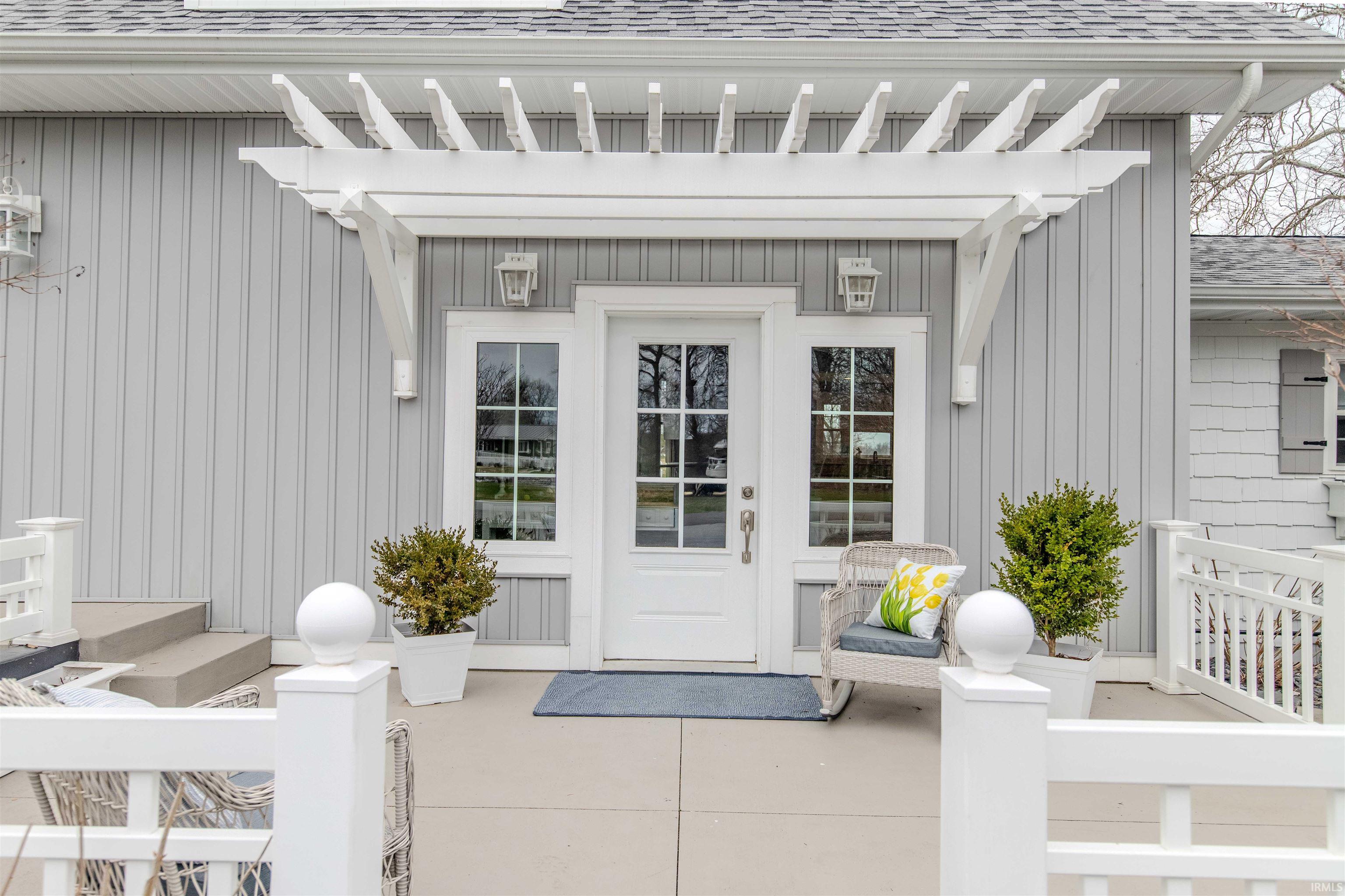 View of exterior entry with roof with shingles and board and batten siding