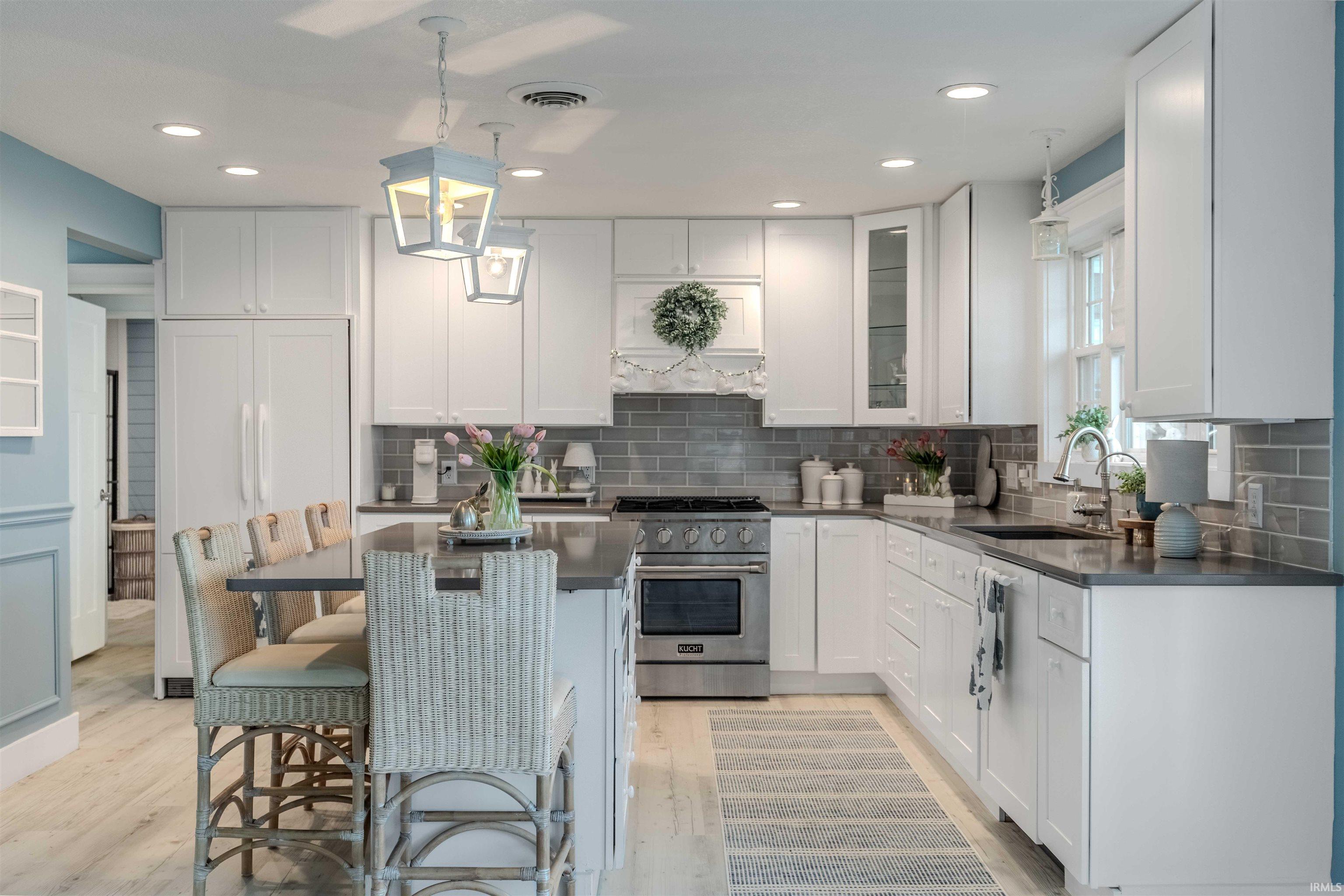 Kitchen featuring a breakfast bar, white cabinets, high end range, a center island, and light wood-style floors