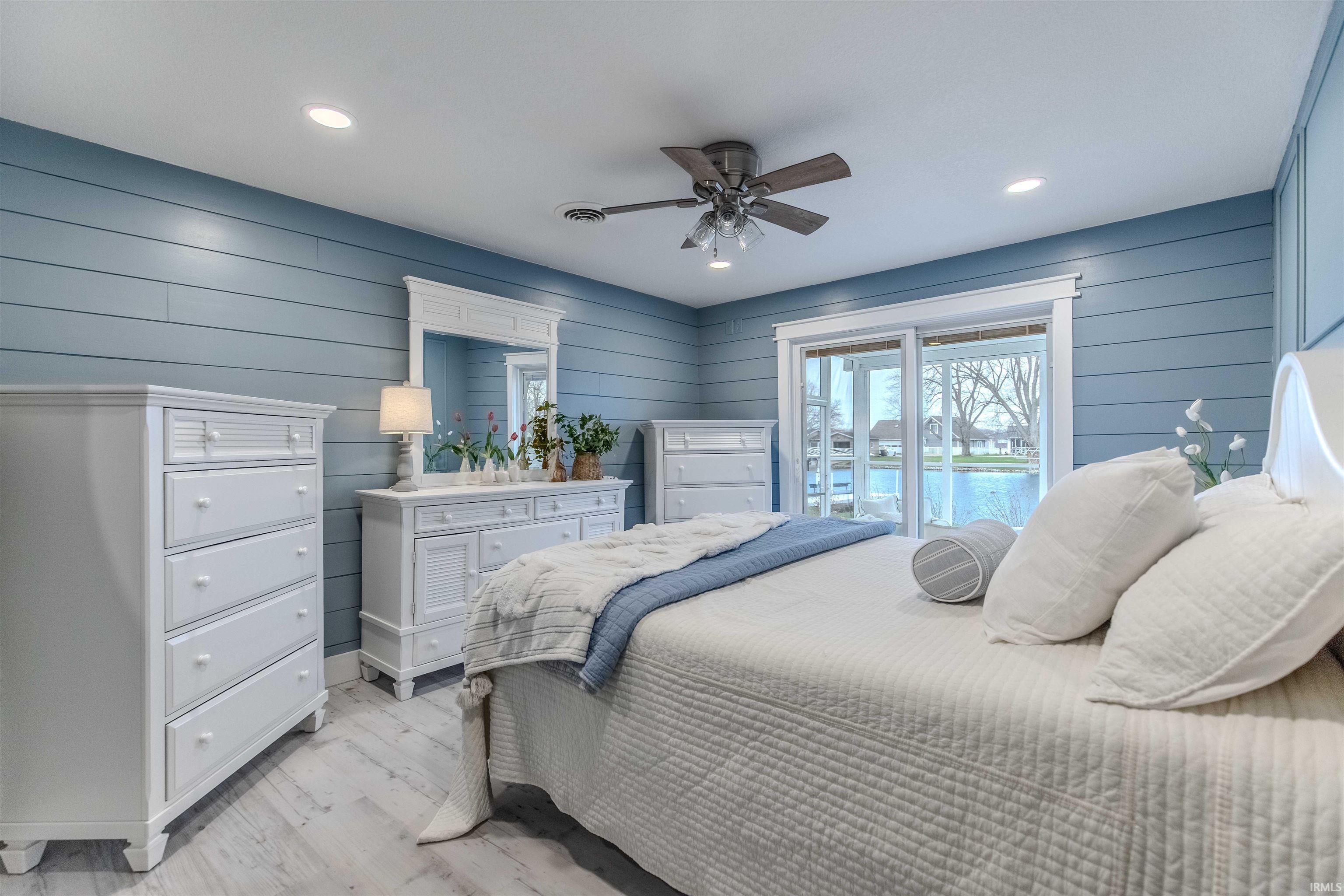 Bedroom with access to exterior, wood walls, a ceiling fan, light wood-type flooring, and recessed lighting