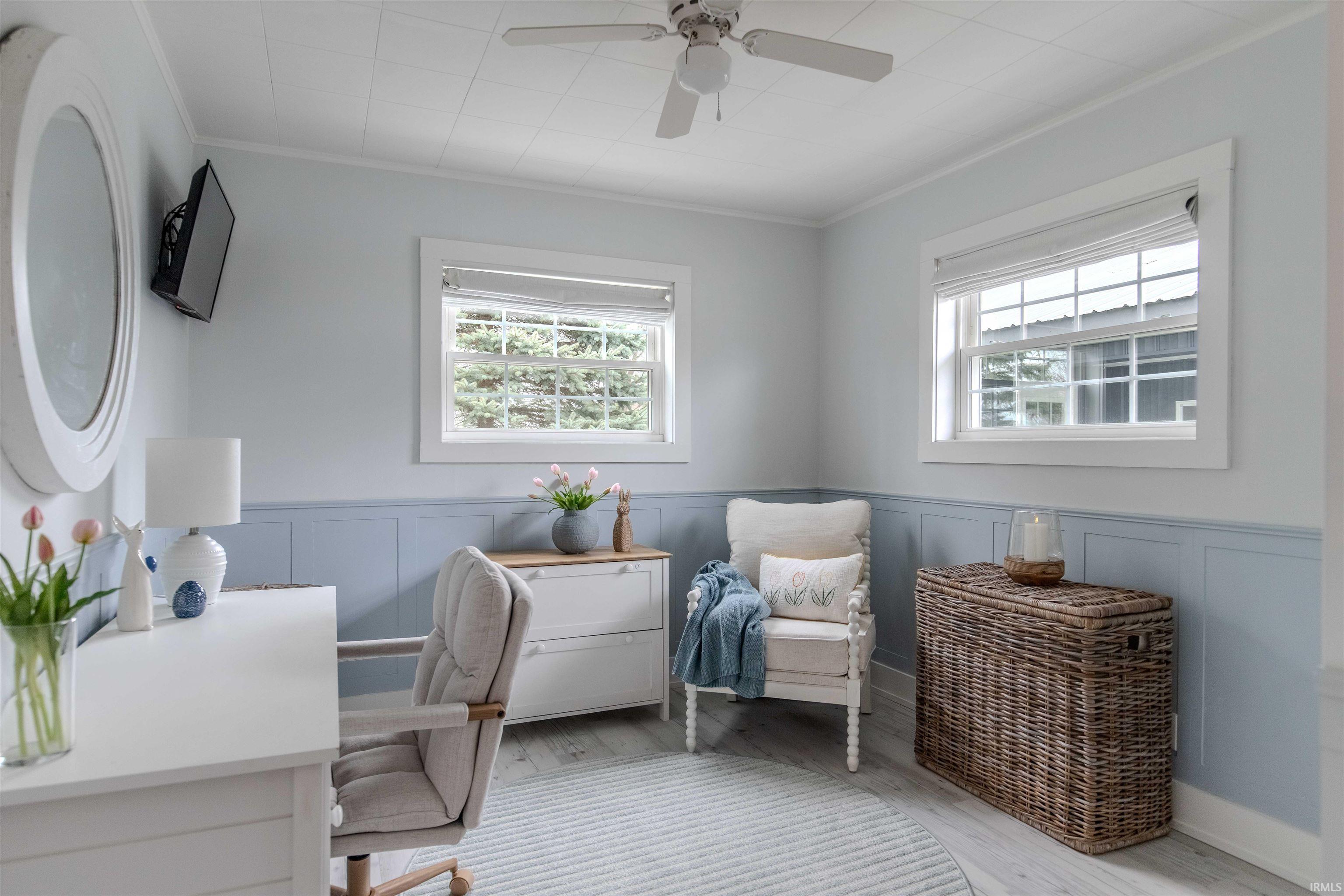 Office with plenty of natural light, a ceiling fan, light wood-style flooring, ornamental molding, and wainscoting
