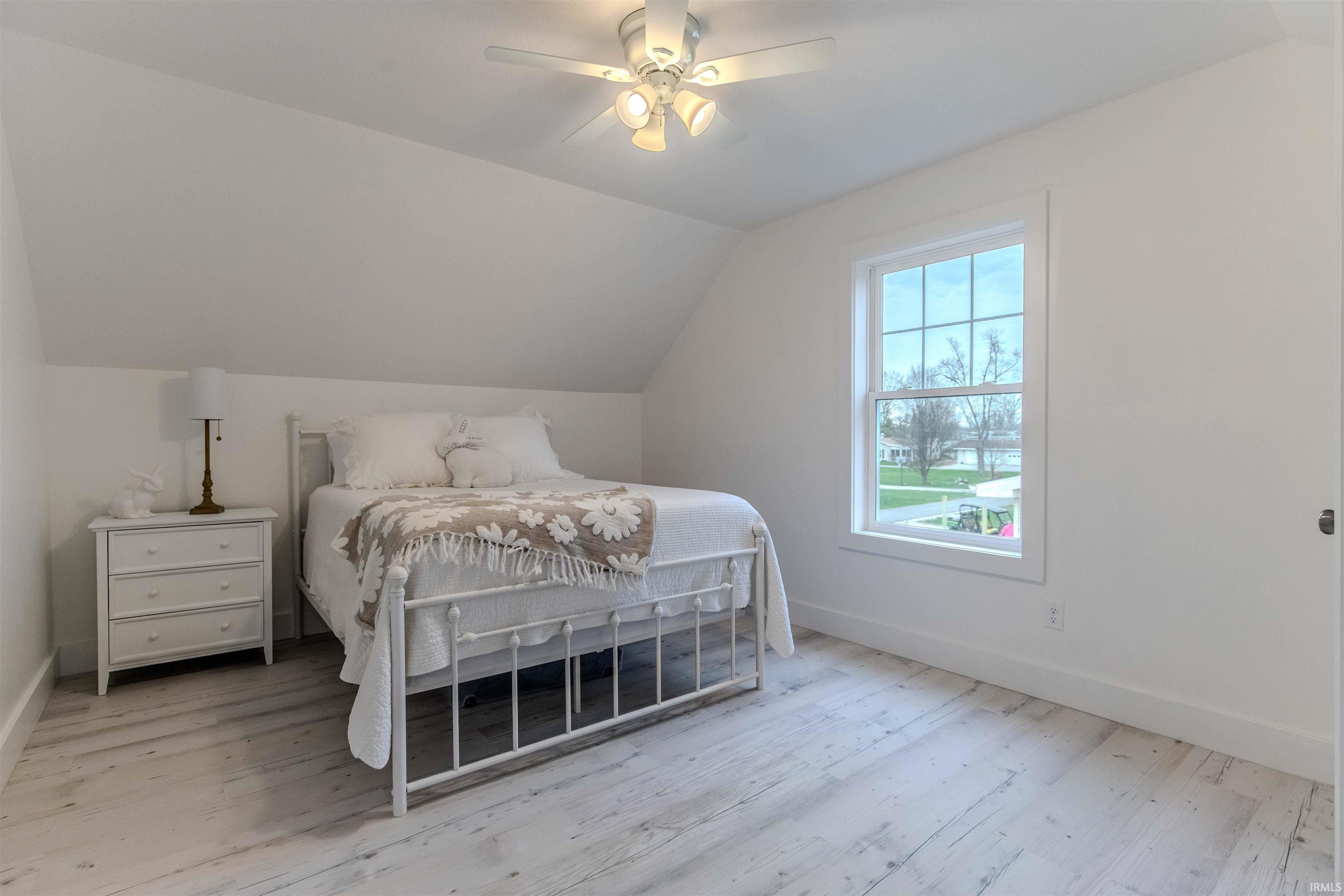 Bedroom featuring vaulted ceiling, a ceiling fan, and light wood-style floors