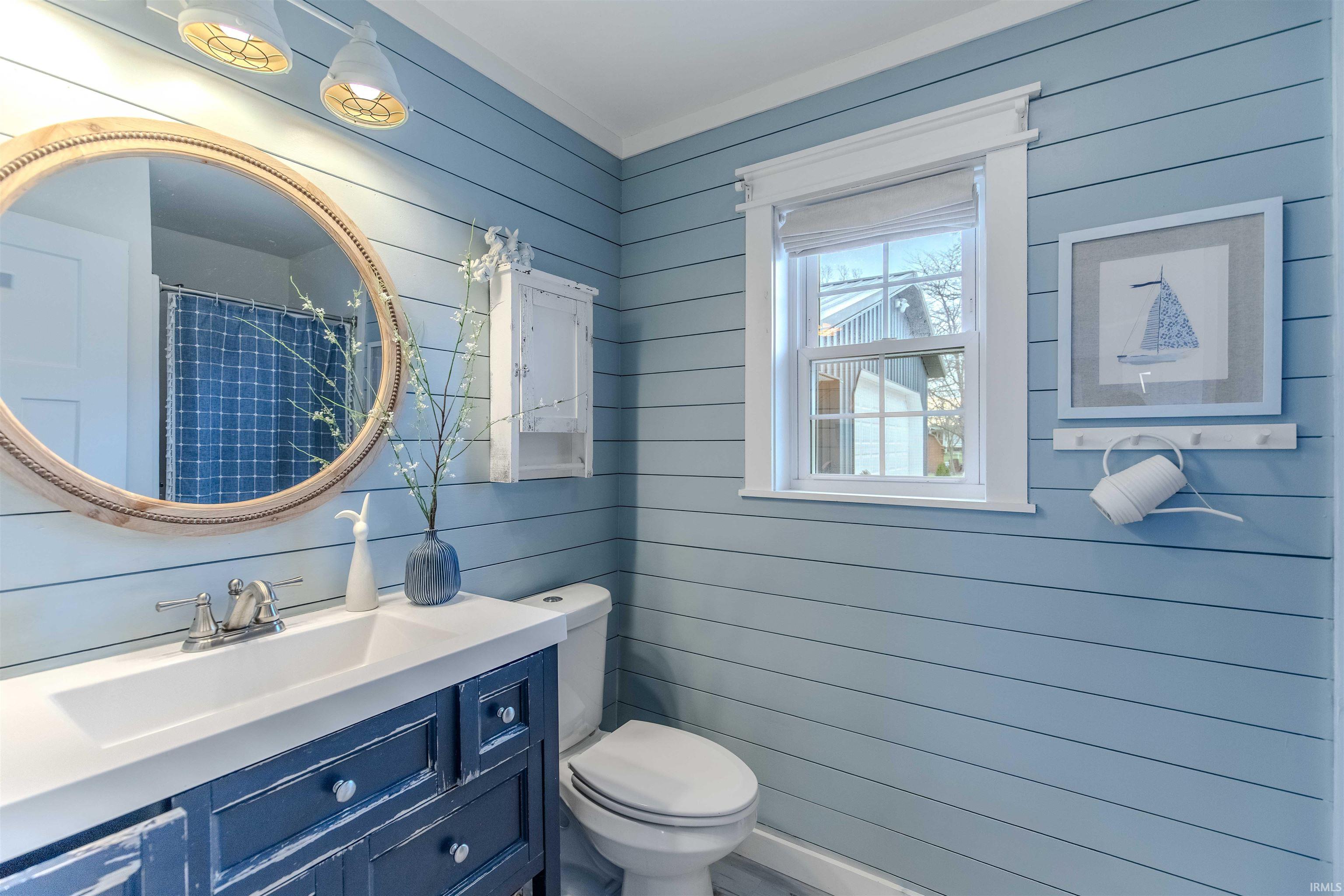 Bathroom featuring wooden walls, vanity, and curtained shower