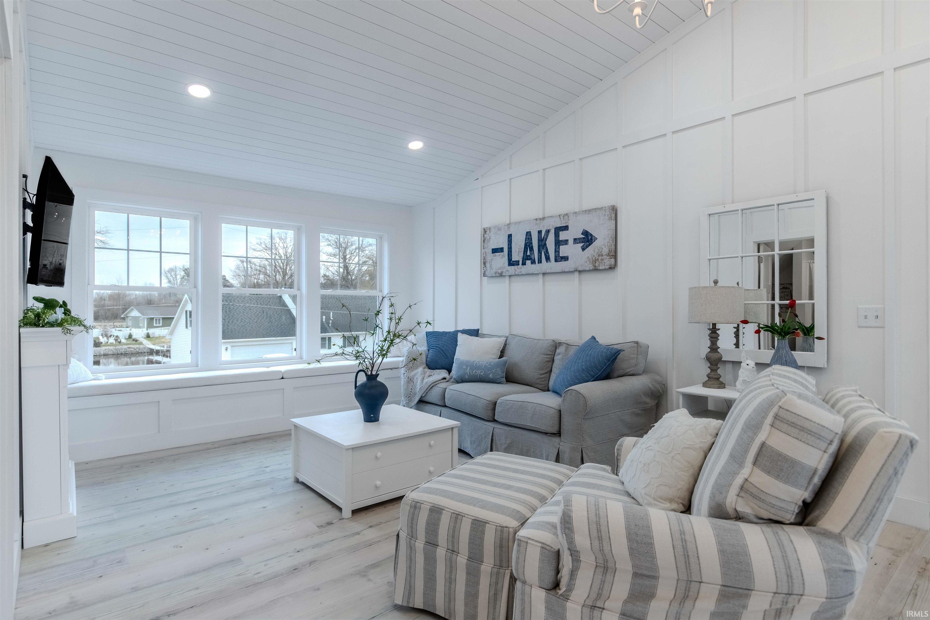 Living room featuring a decorative wall, light wood-style flooring, vaulted ceiling, and recessed lighting