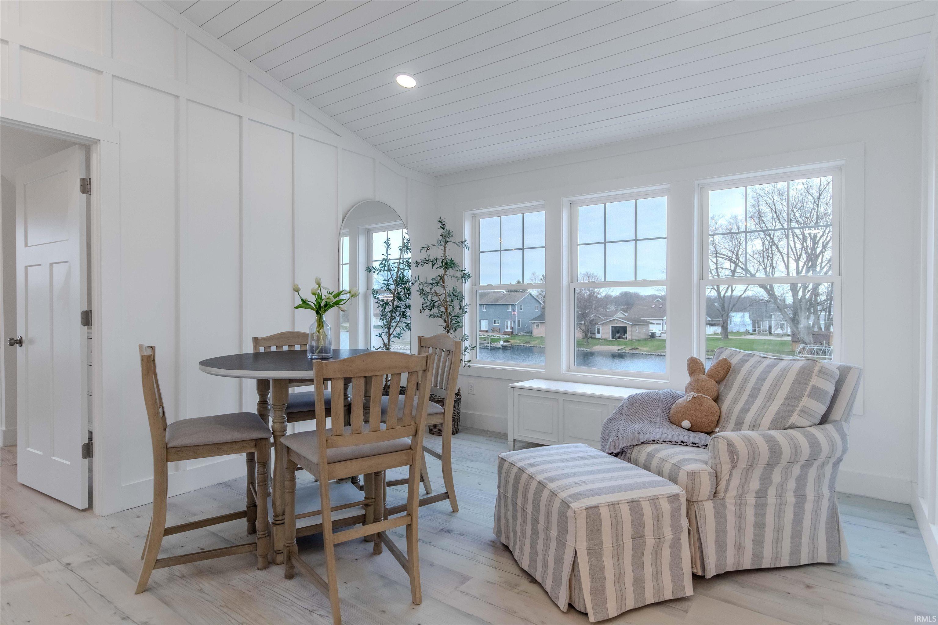 Dining area featuring a decorative wall, lofted ceiling, light wood finished floors, recessed lighting, and a residential view