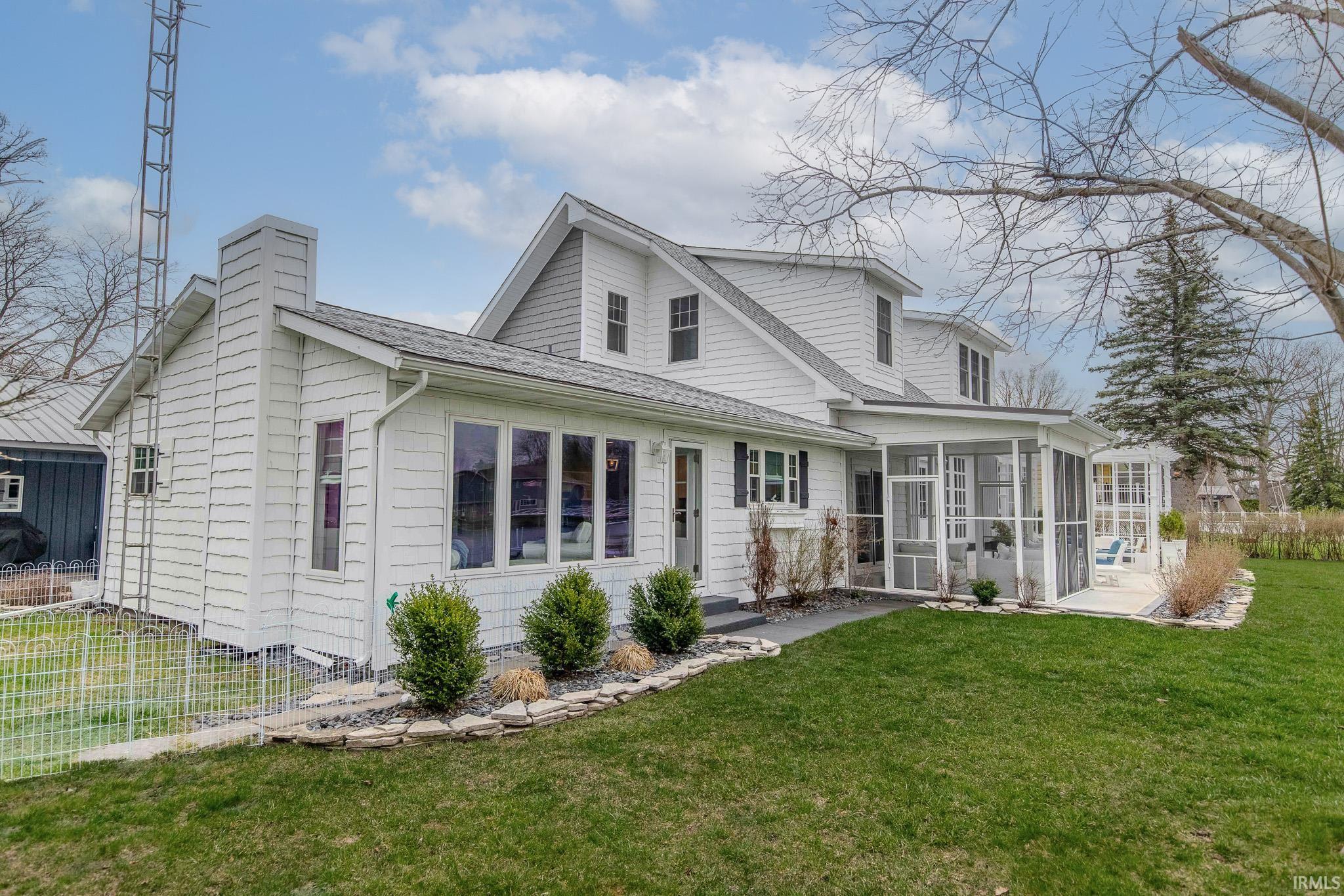 Back of property with roof with shingles, a lawn, a sunroom, and a chimney