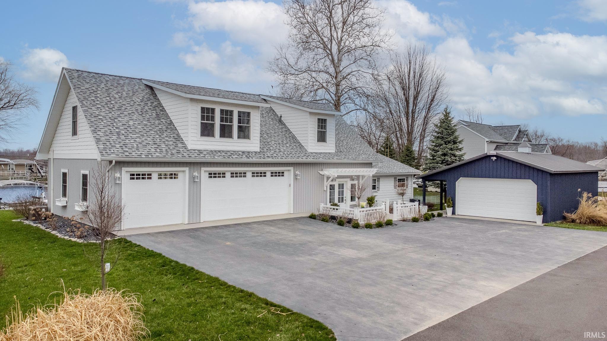 View of front facade featuring roof with shingles, an outbuilding, and a garage