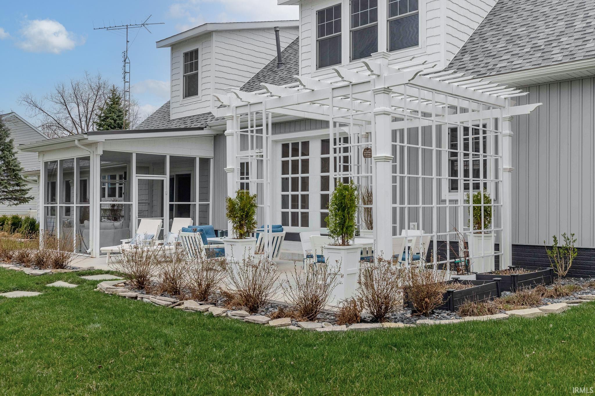 Back of property featuring a shingled roof, a sunroom, a patio, and a yard