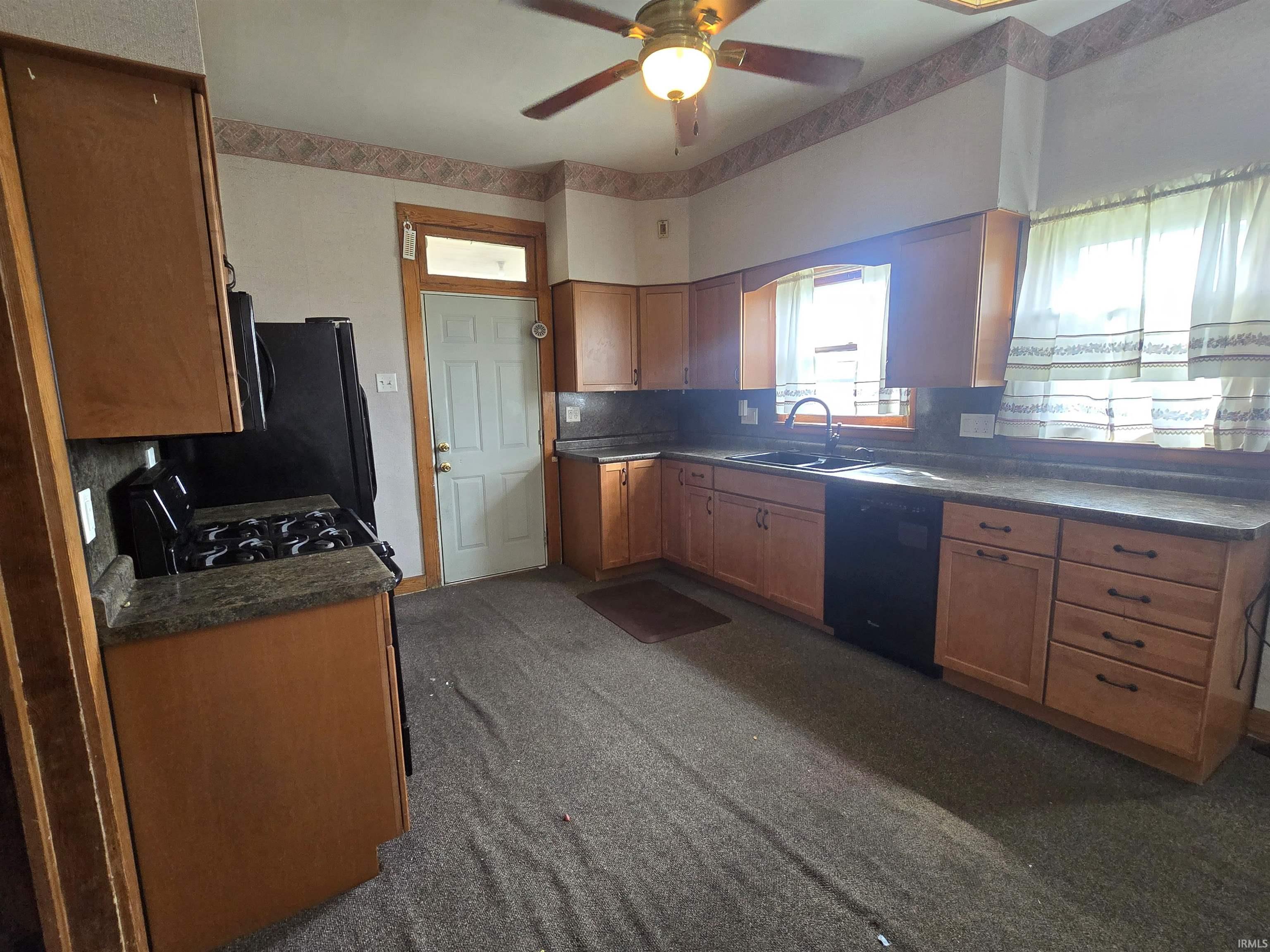 Kitchen featuring black appliances, a ceiling fan, decorative backsplash, dark countertops, and wood finish cabinetry