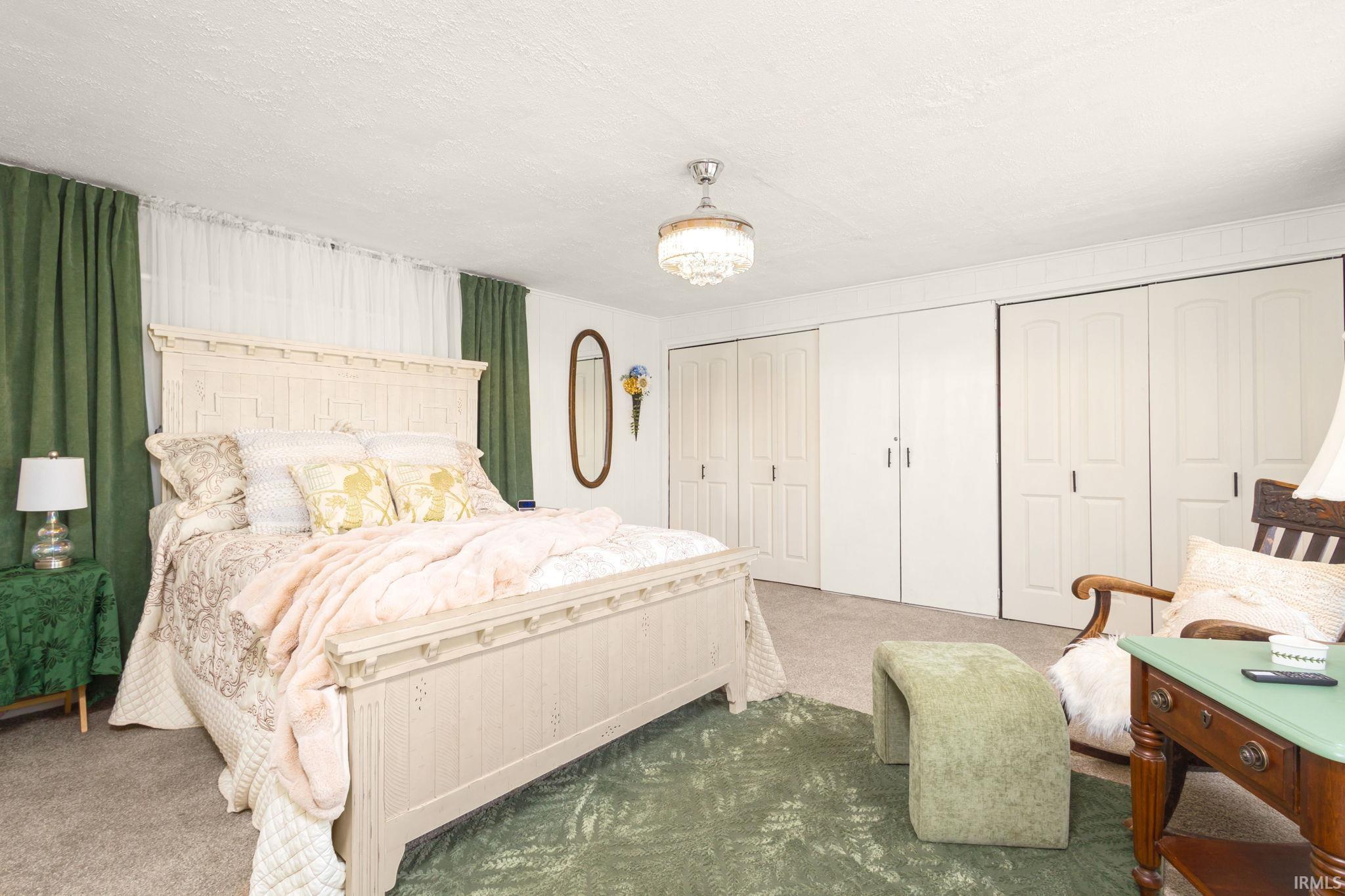 Bedroom with two closets, carpet floors, and a textured ceiling