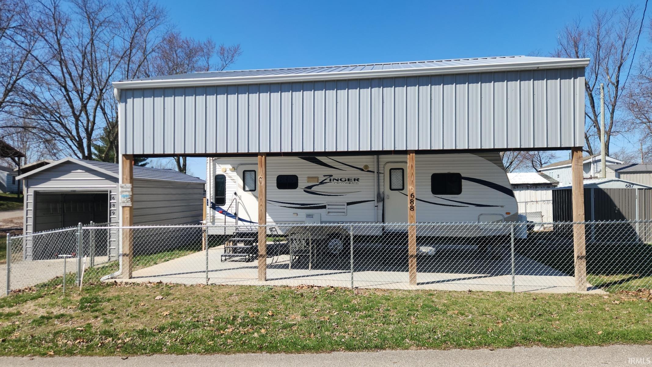 View of parking featuring a shed, a carport, and a detached garage