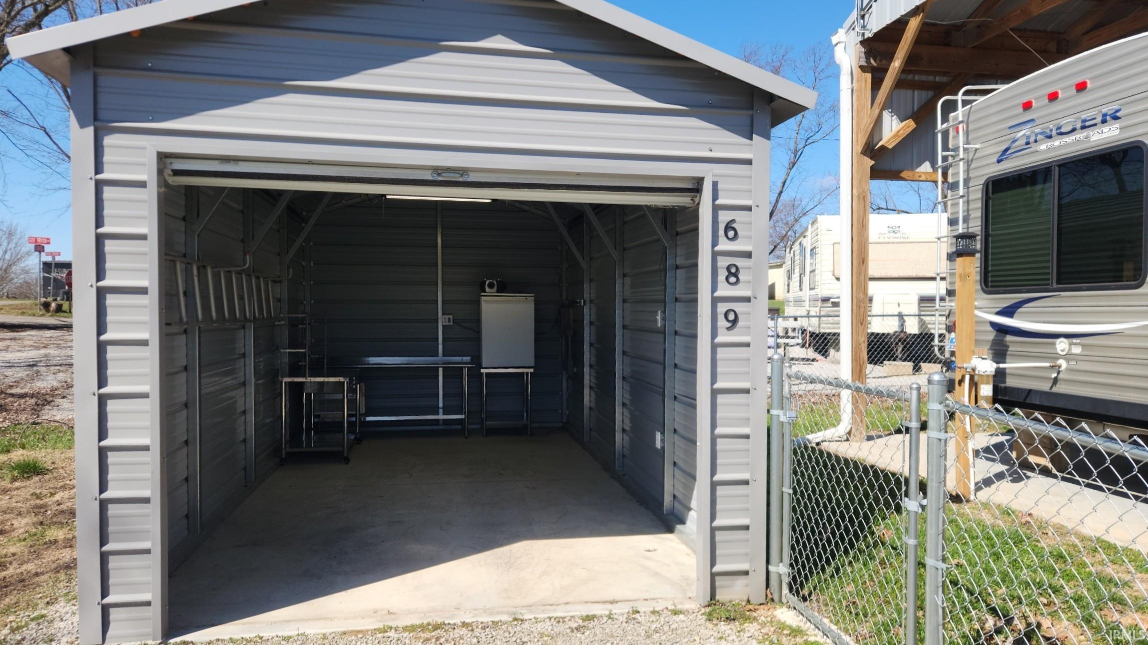 View of parking featuring a detached garage and a gate