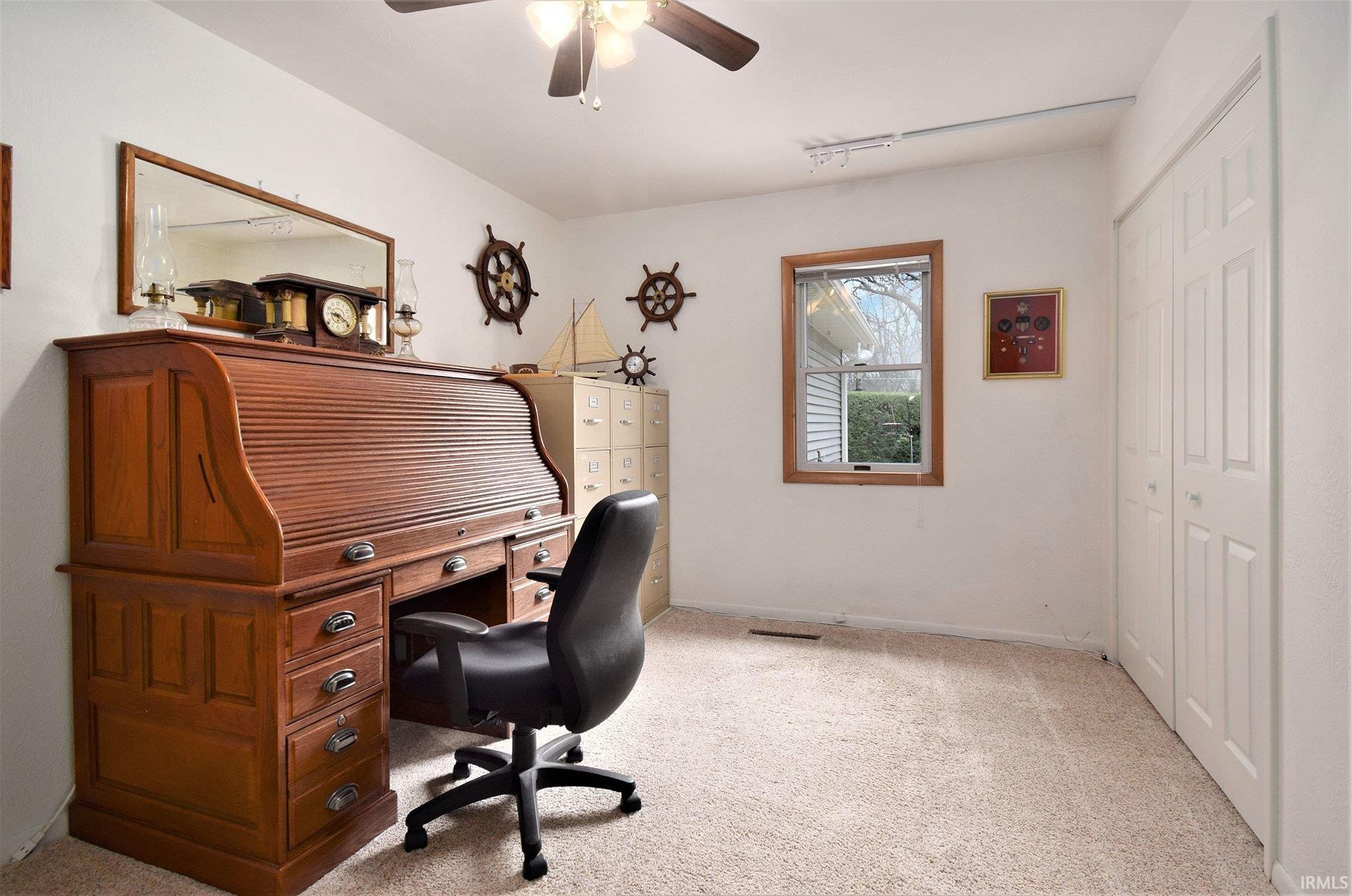 Home office featuring light carpet and ceiling fan