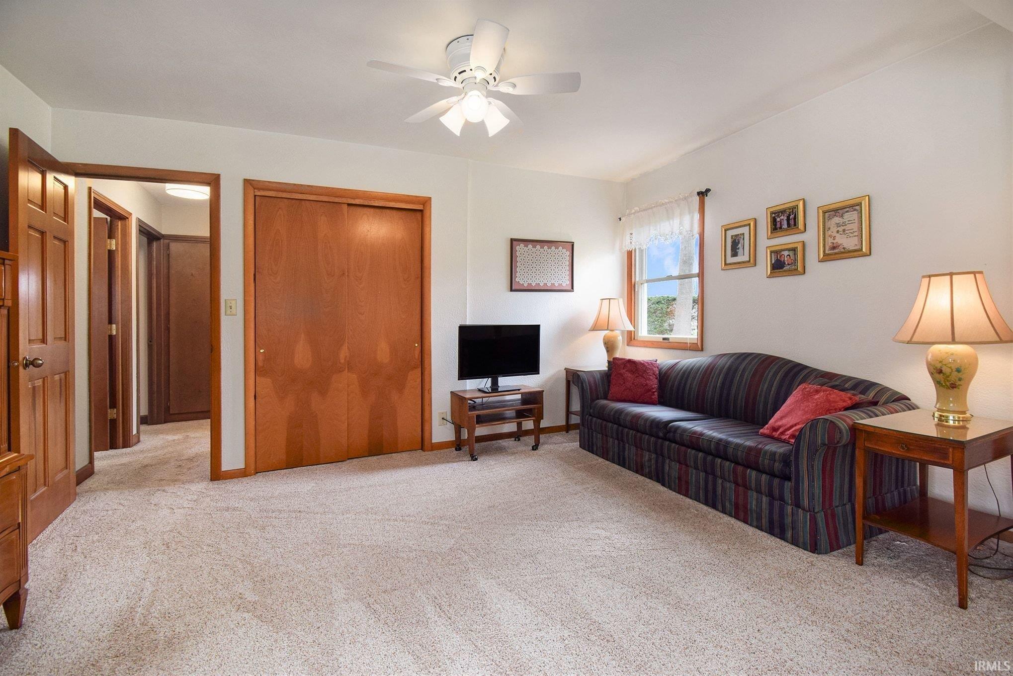 Living room with ceiling fan and light colored carpet