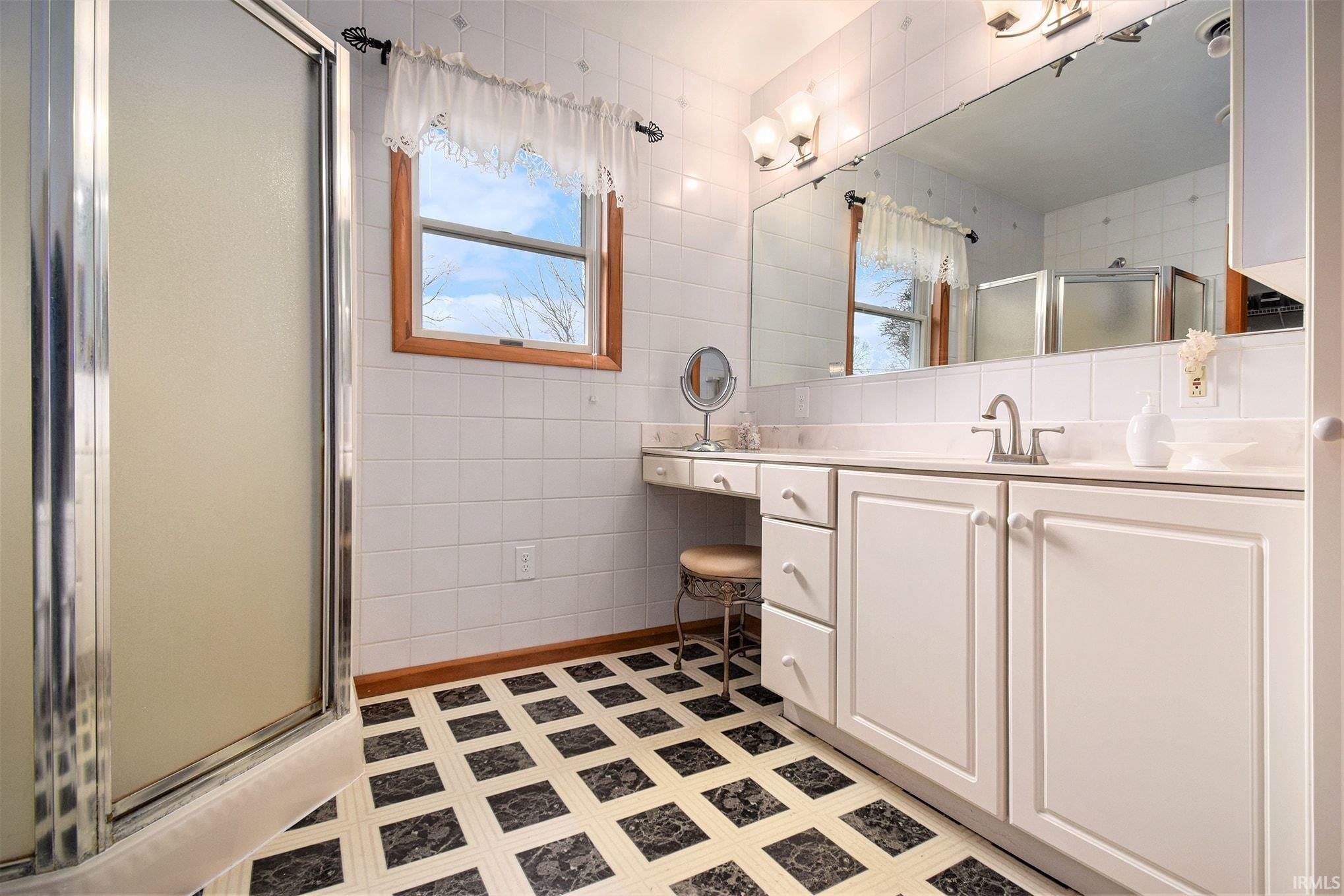 Full bath with vanity, tile walls, and a shower stall