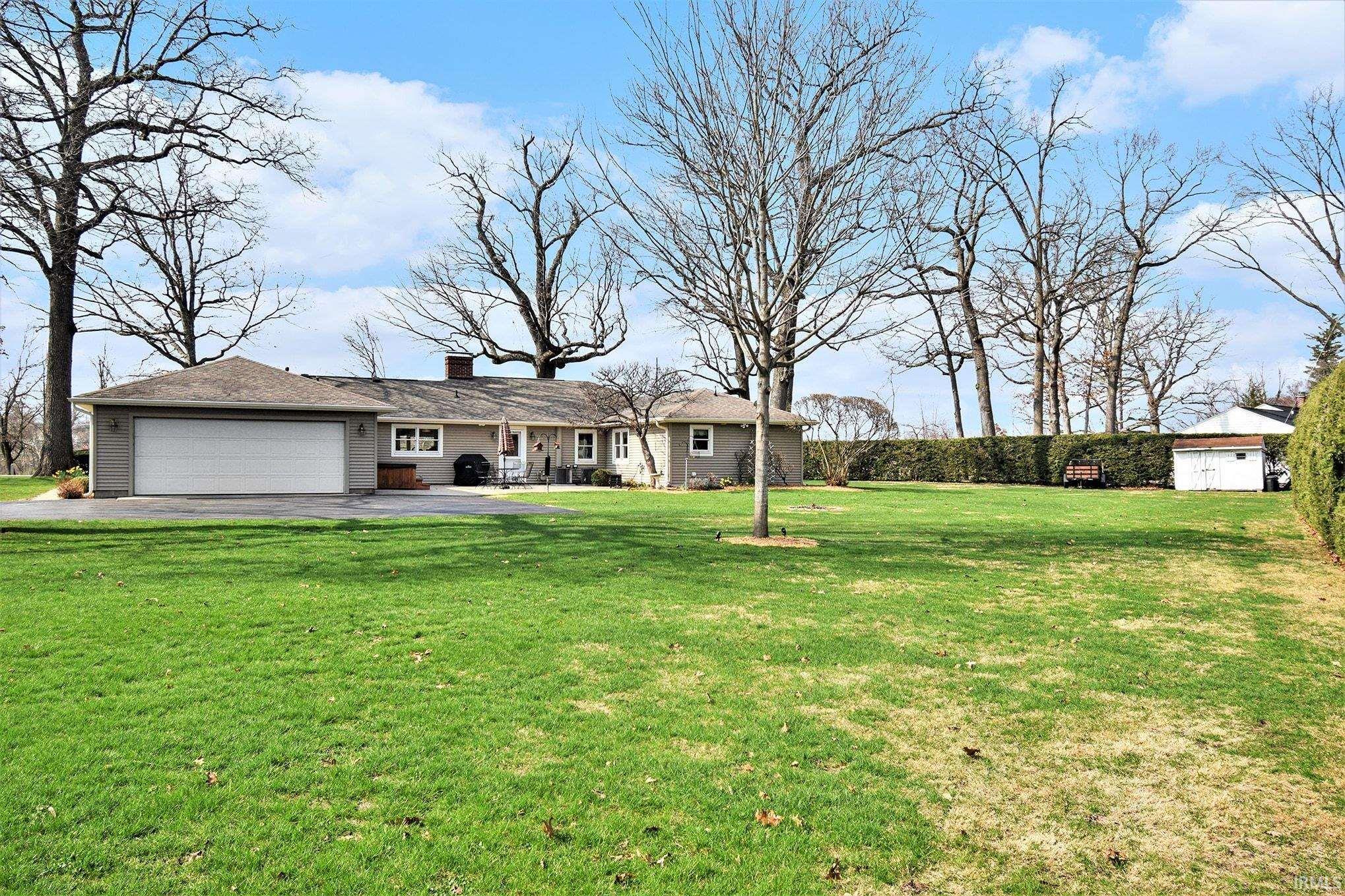 Ranch-style home featuring a front yard, an attached garage, asphalt driveway, and a chimney
