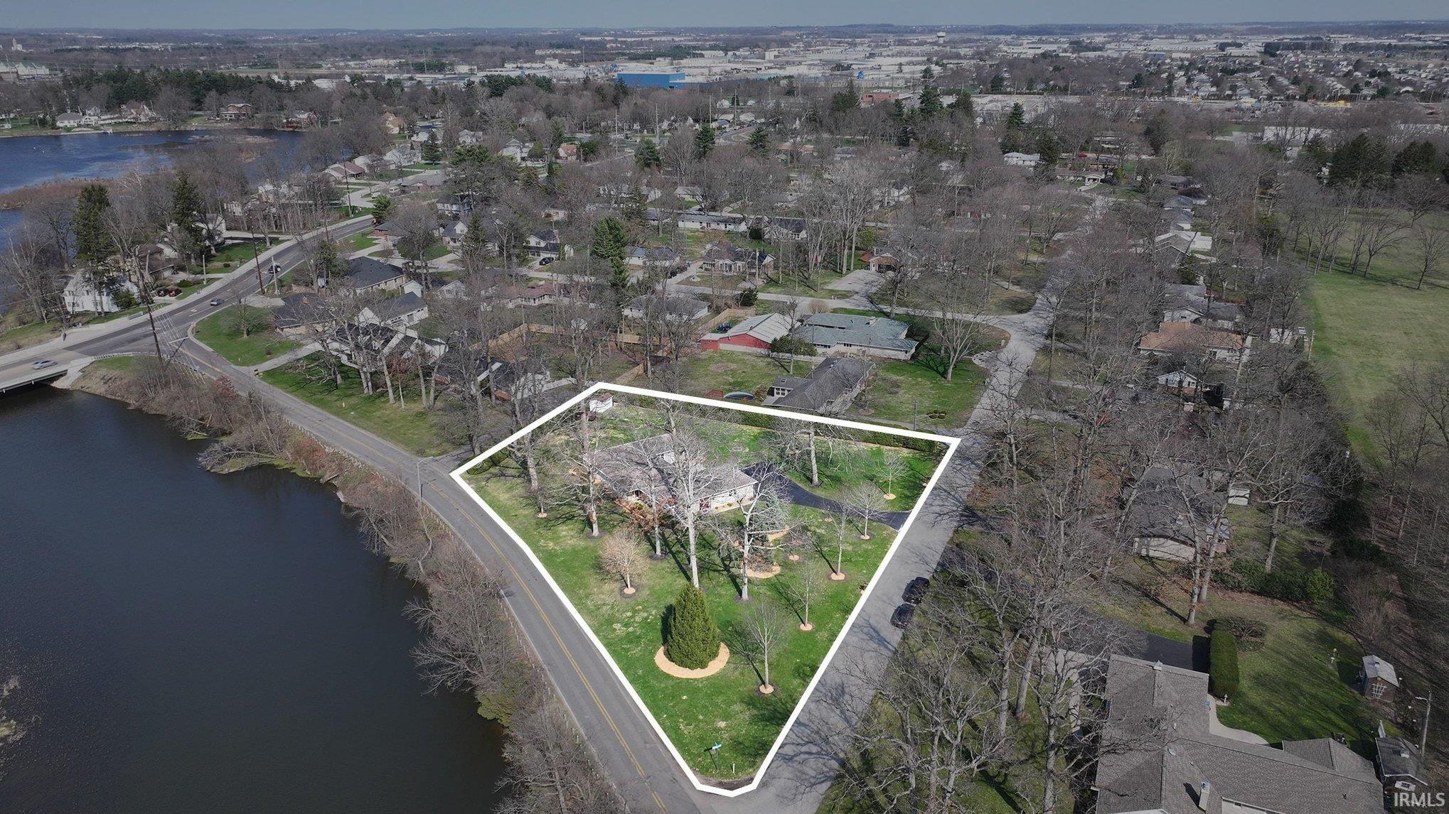 Aerial view of residential area with a large body of water and property boundaries highlighted