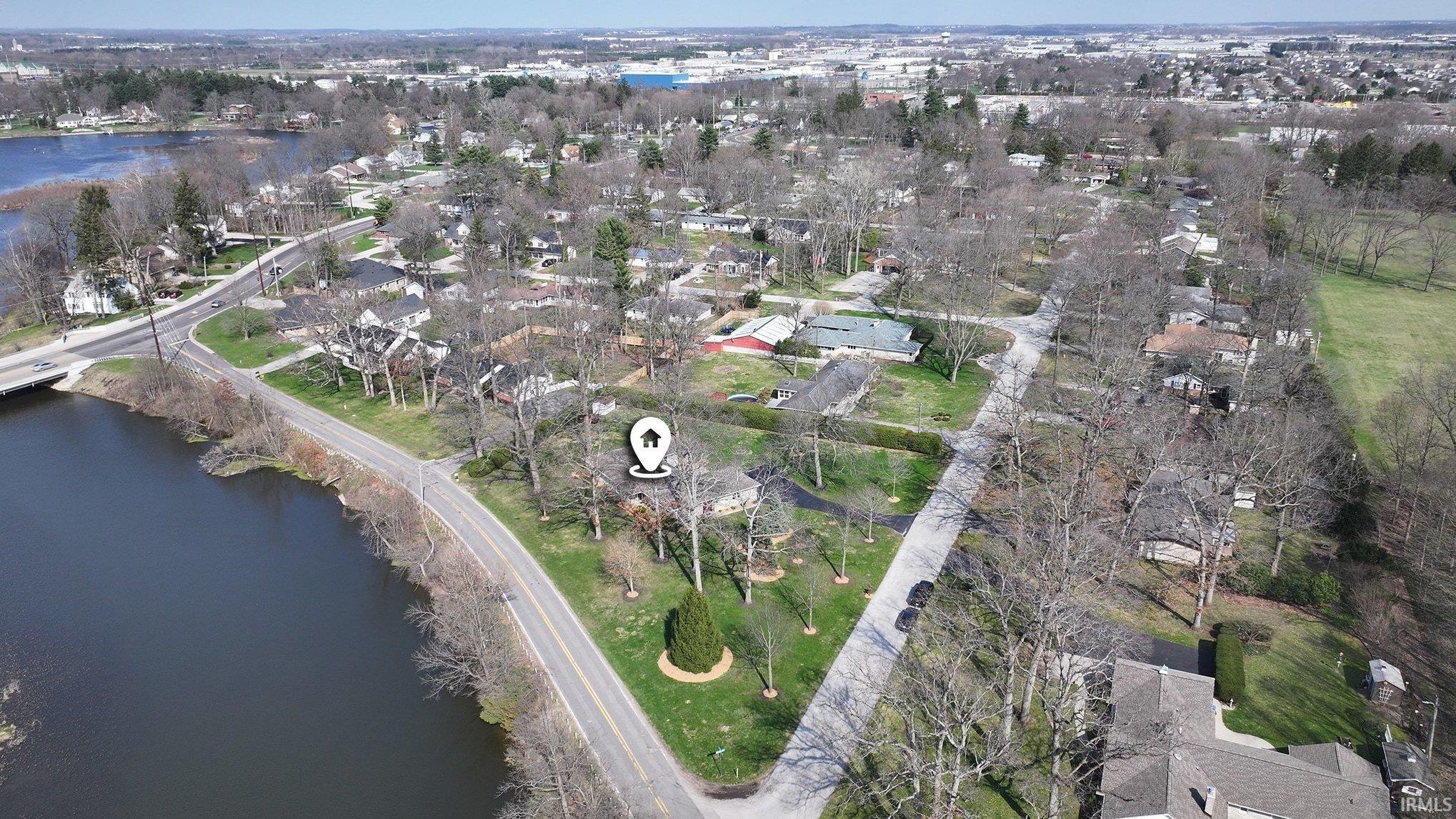 Aerial view of property and surrounding area featuring nearby suburban area and a large body of water