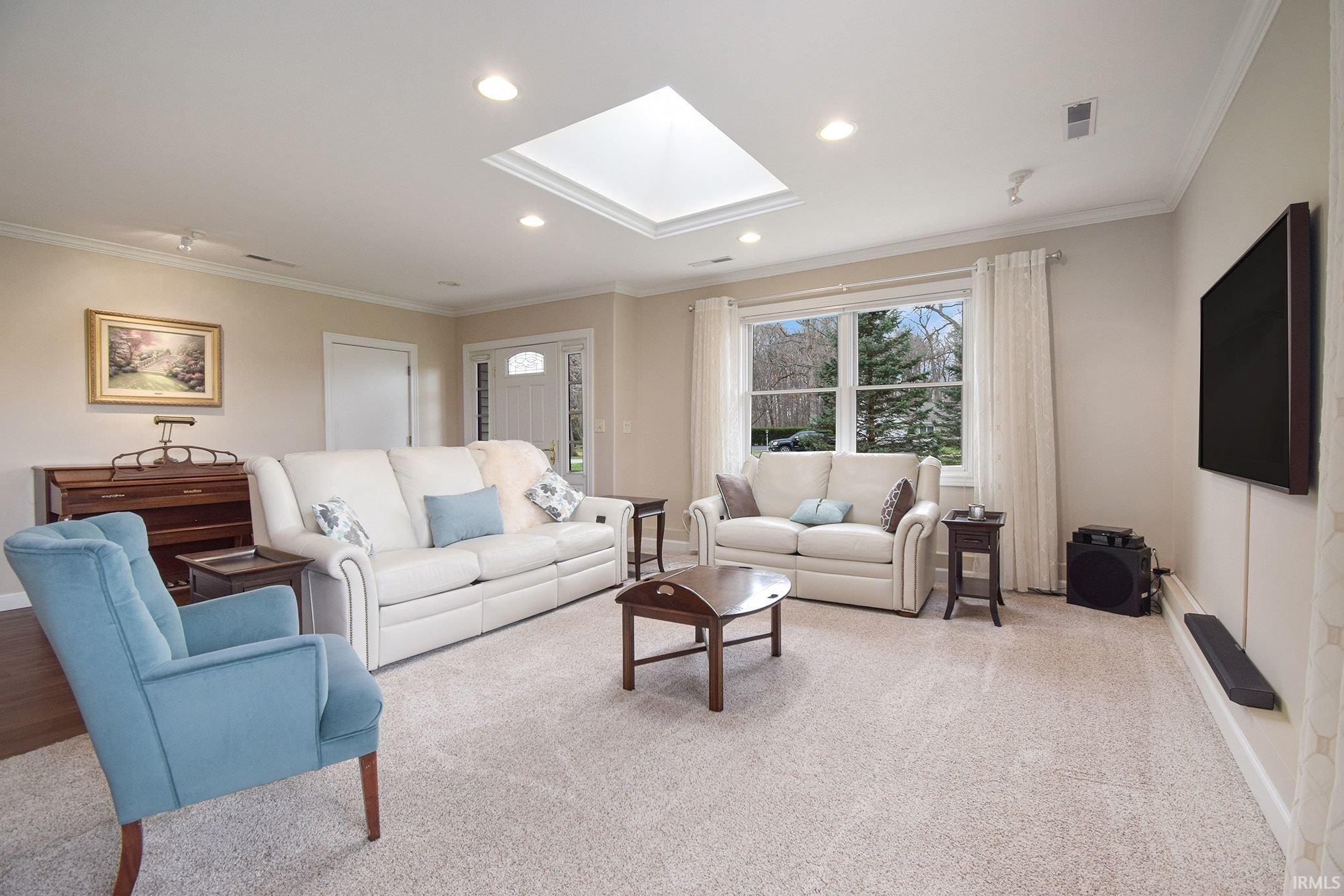 Carpeted living room with crown molding, a skylight, and recessed lighting