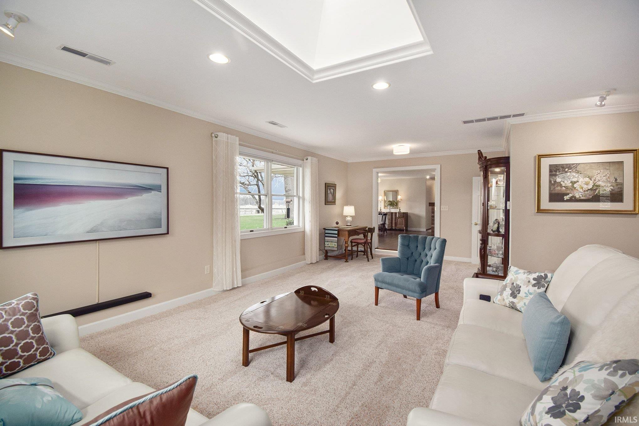 Living room featuring ornamental molding, recessed lighting, light carpet, and a skylight
