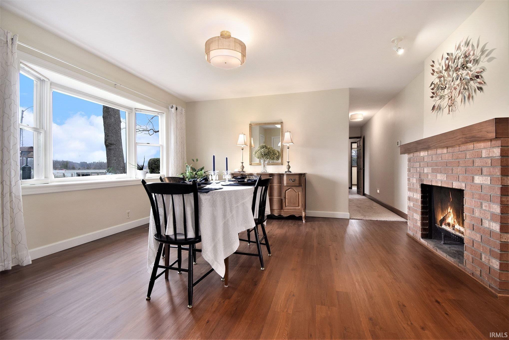 Dining area with dark wood finished floors and a brick fireplace