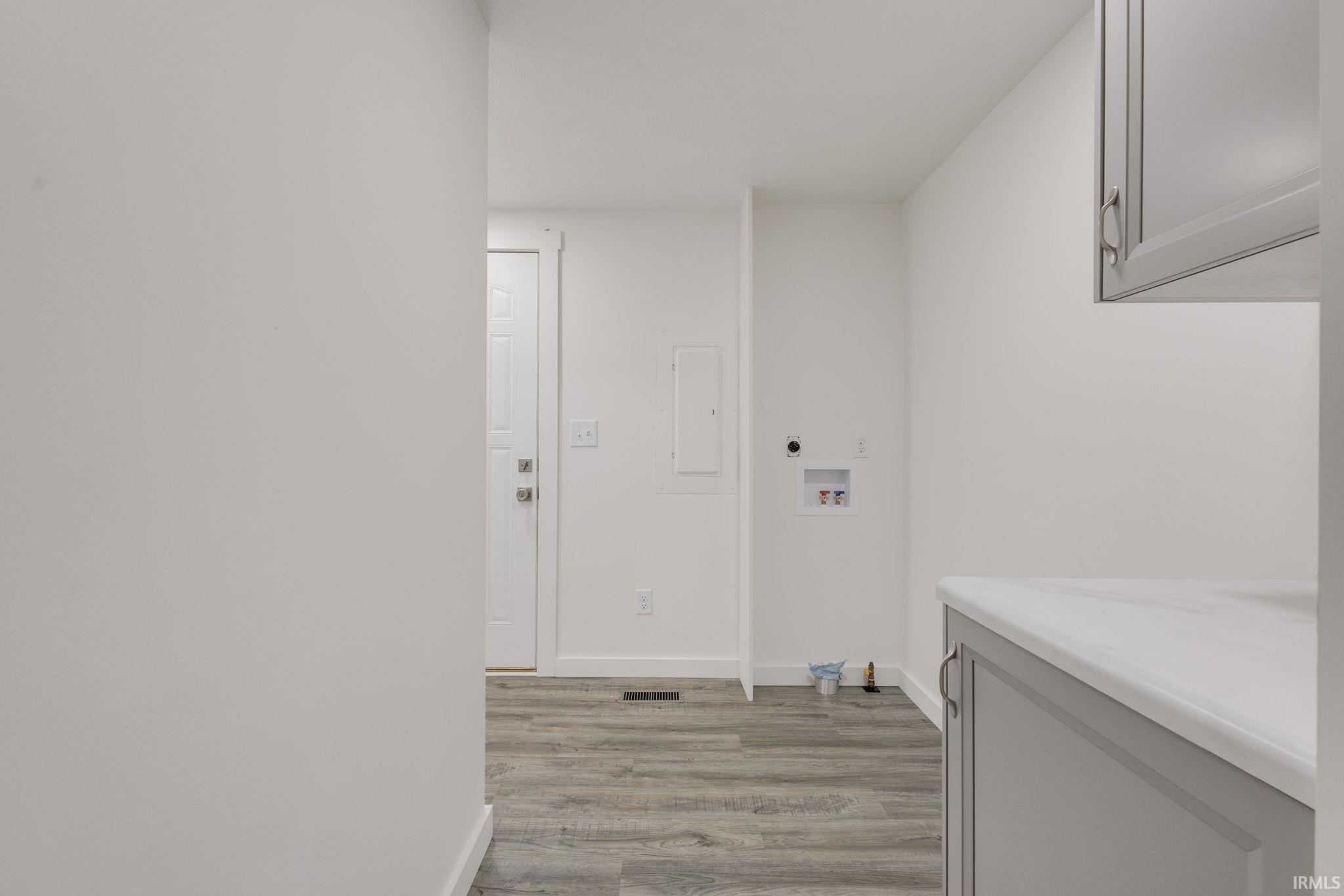 Laundry area featuring light wood-type flooring, hookup for a washing machine, and cabinet space