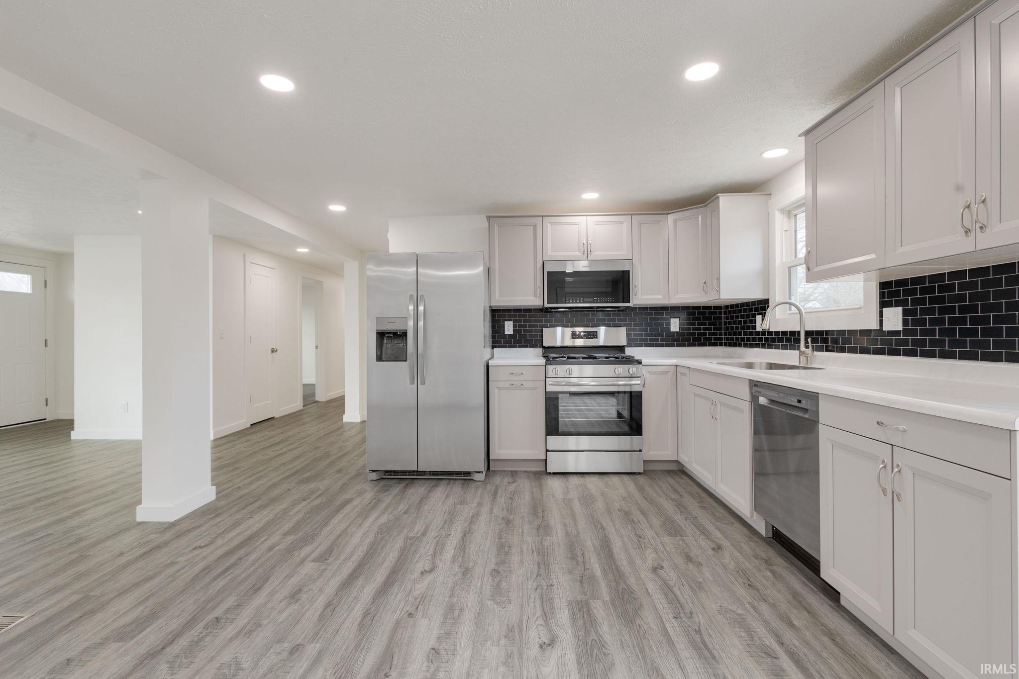 Kitchen featuring stainless steel appliances, light countertops, light wood-style flooring, recessed lighting, and decorative backsplash