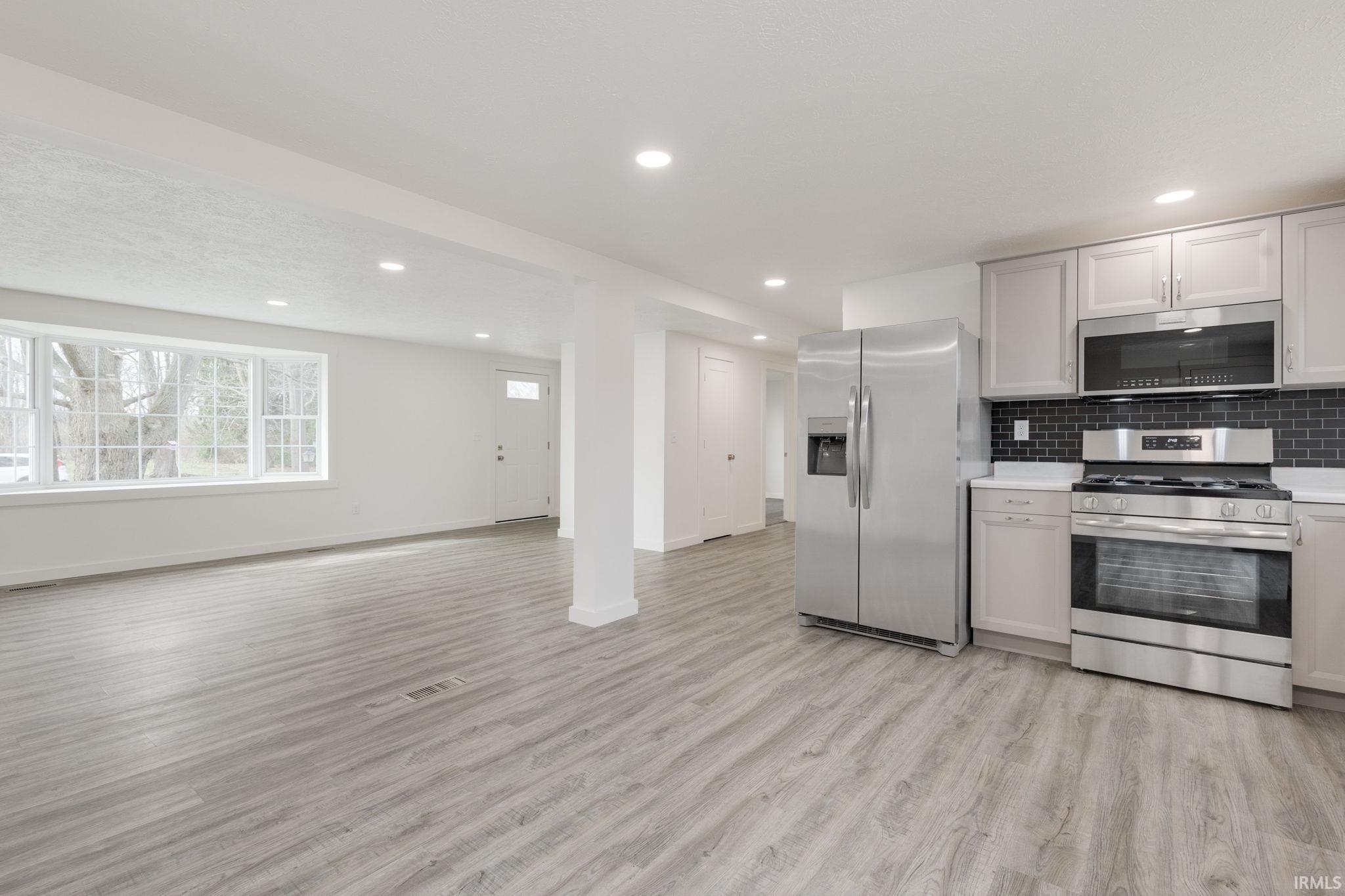Kitchen featuring stainless steel appliances, light wood-style flooring, recessed lighting, open floor plan, and tasteful backsplash