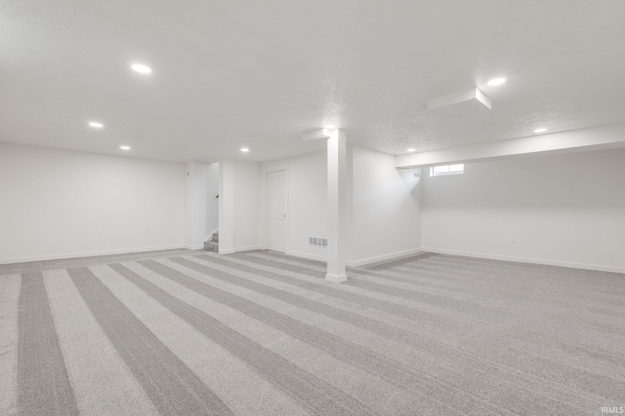 Basement with light carpet and recessed lighting