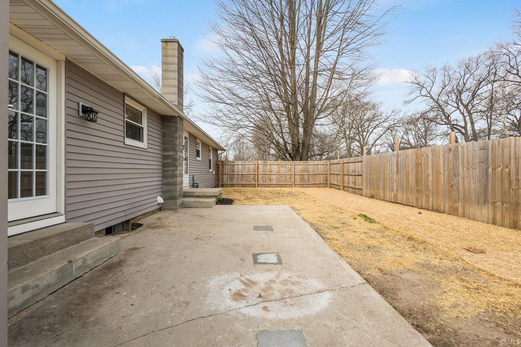 Fenced backyard with entry steps and a patio area