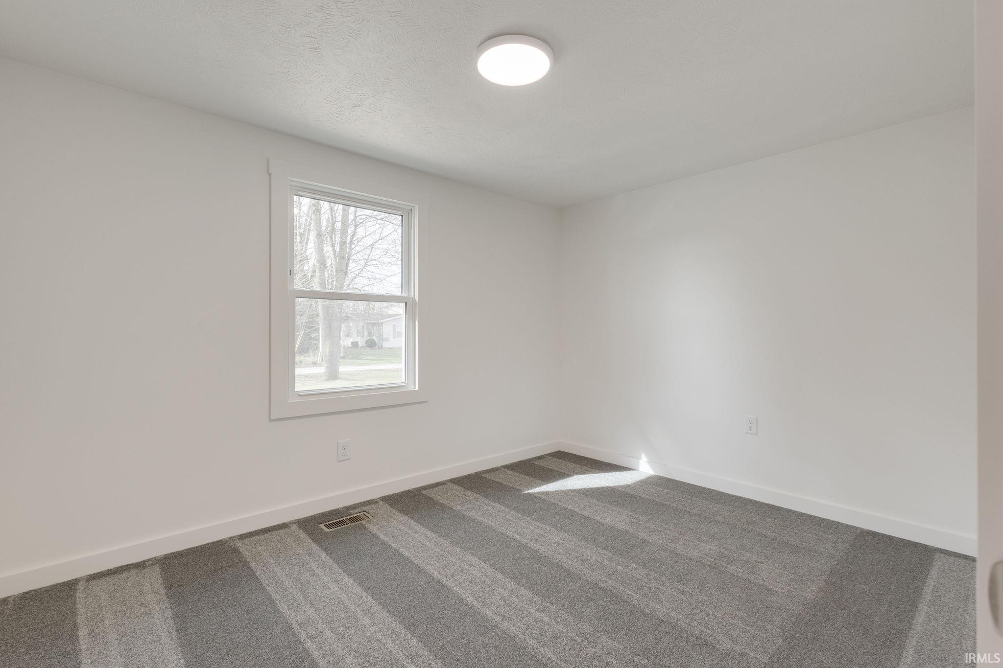 Unfurnished room featuring dark colored carpet and baseboards