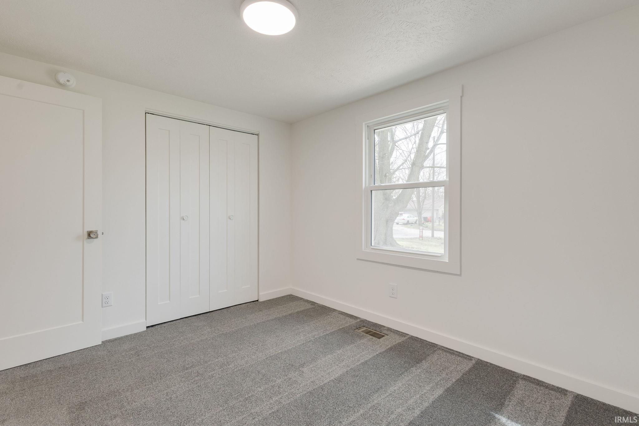 Unfurnished bedroom featuring dark colored carpet and a closet