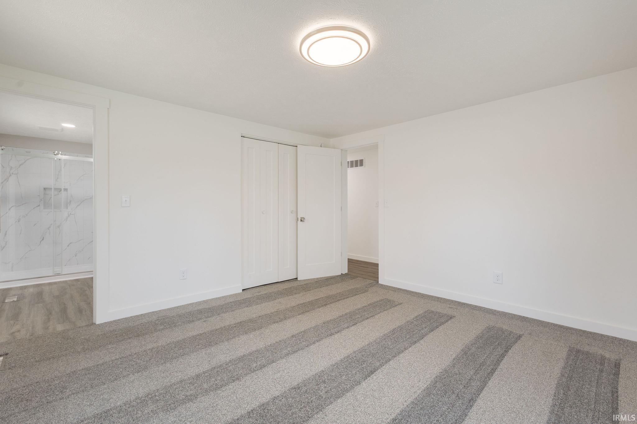 Primary bedroom with carpet floors, a closet, and ensuite bath