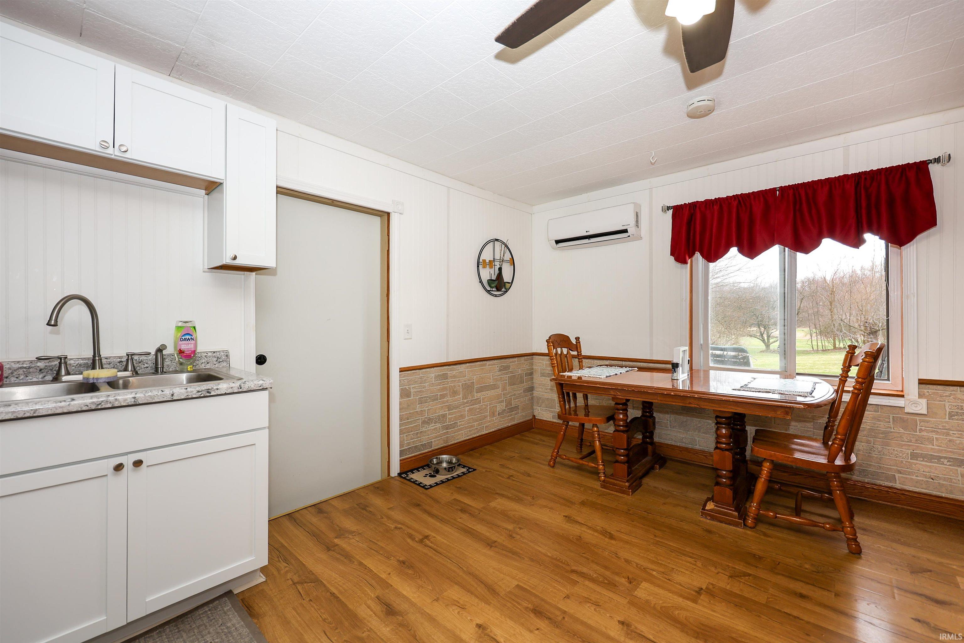 Dining room featuring light wood-style flooring, a ceiling fan, and a wainscoted wall