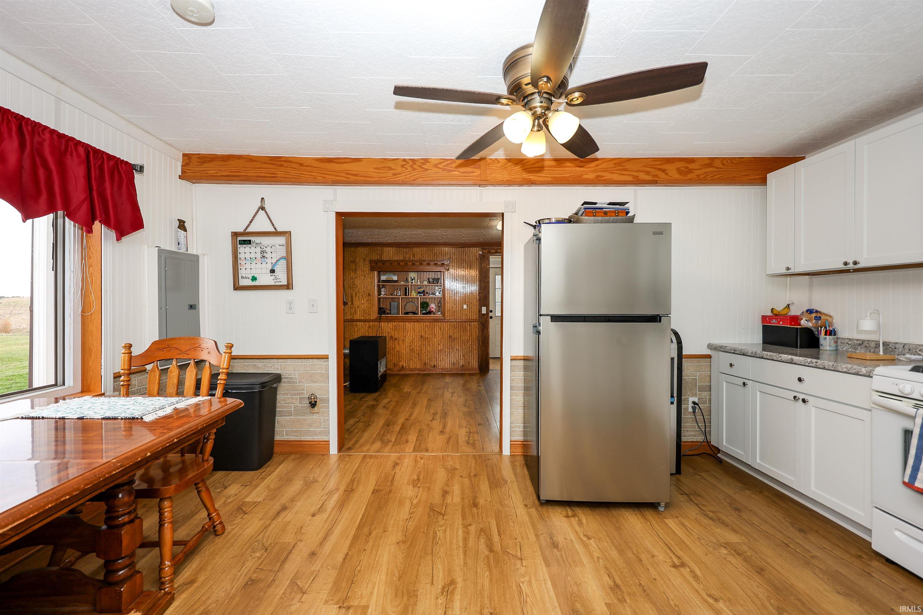 Kitchen featuring freestanding refrigerator, light wood-style floors, white range with gas stovetop, a ceiling fan, and white cabinetry
