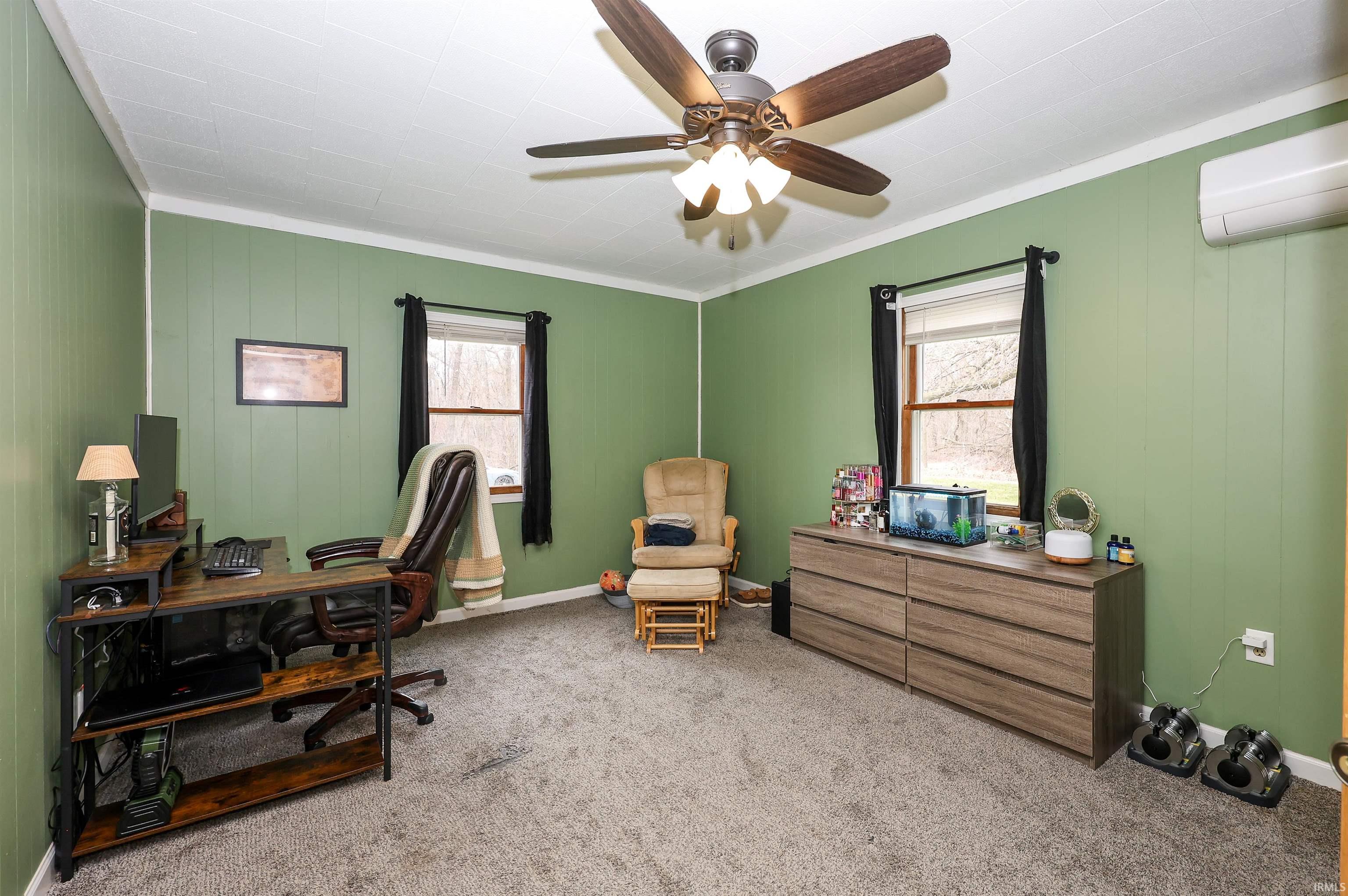 Office featuring plenty of natural light, light carpet, ceiling fan, and wooden walls