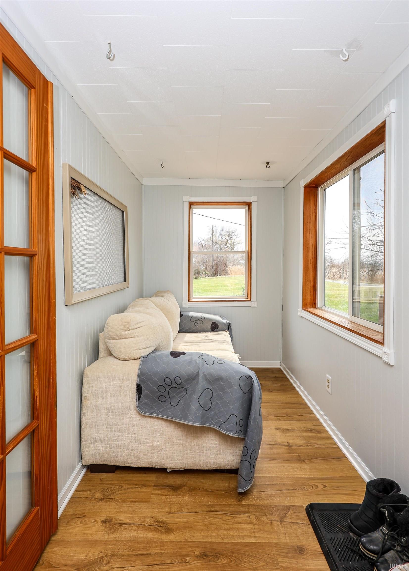 Bedroom featuring wood finished floors, multiple windows, and wooden walls