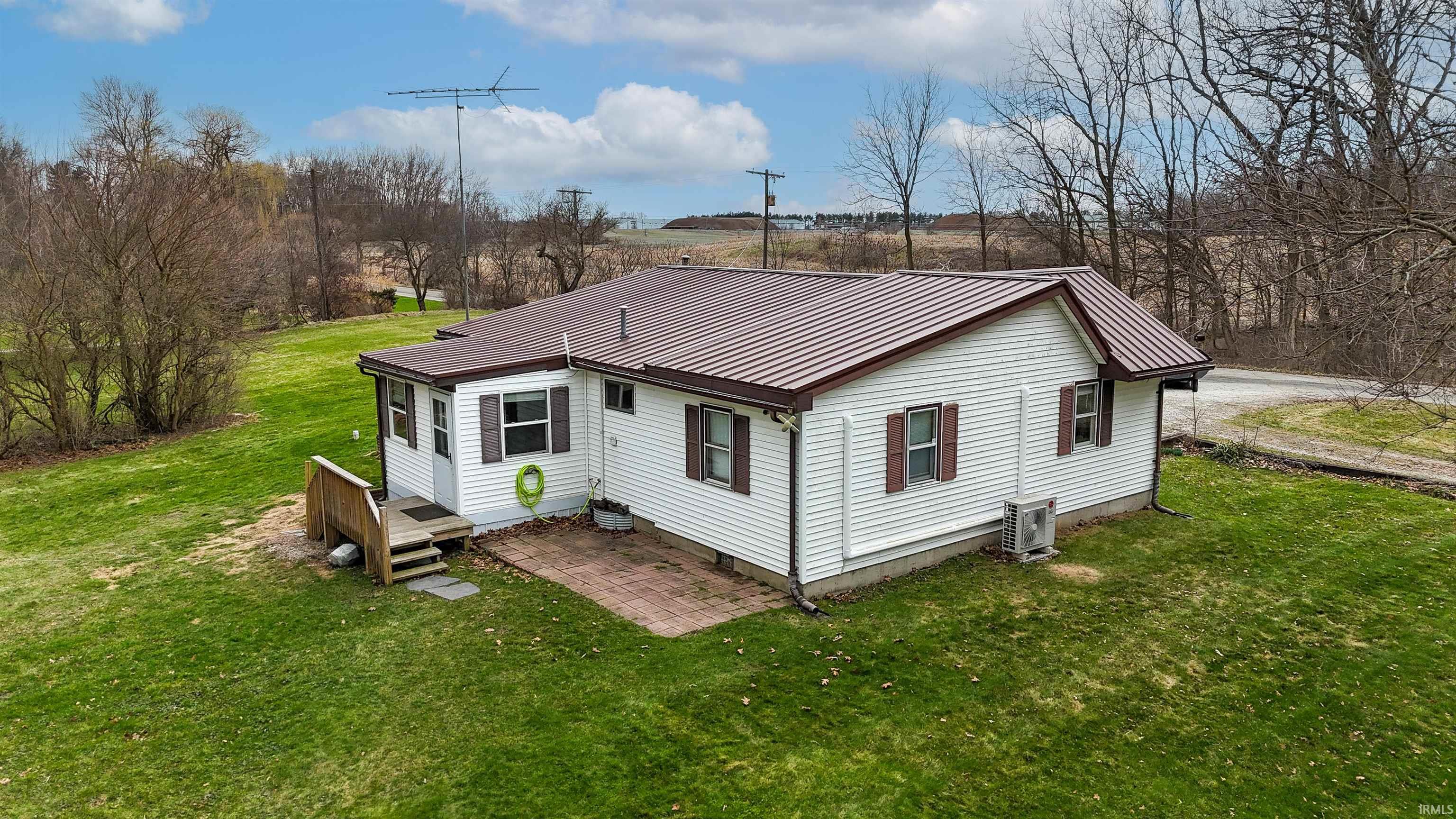 Rear view of property with a yard, a metal roof, and a wooden deck